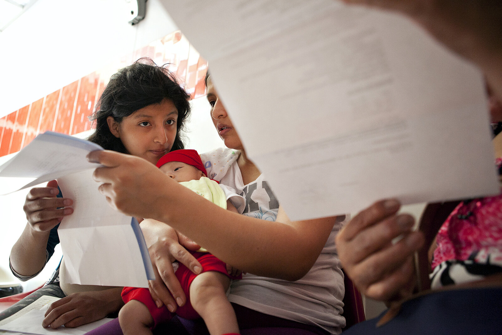 Yoselin looks at paperwork with her mother and grandmother at a clinic in Lima, Peru.