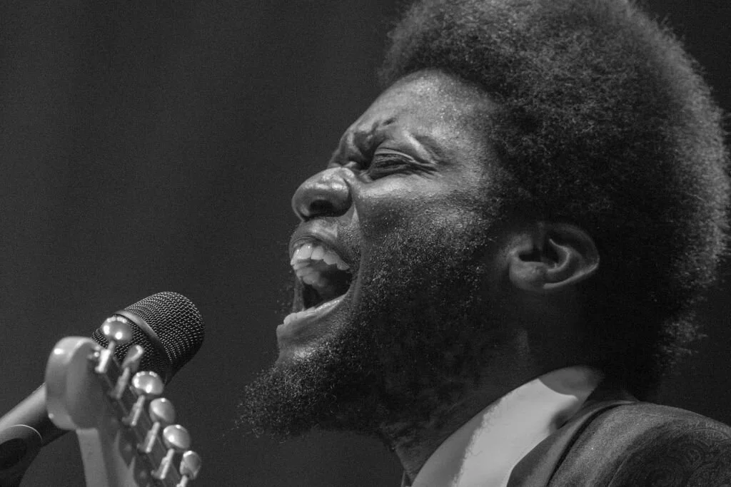 Black and white photo of a man singing passionately into a microphone.