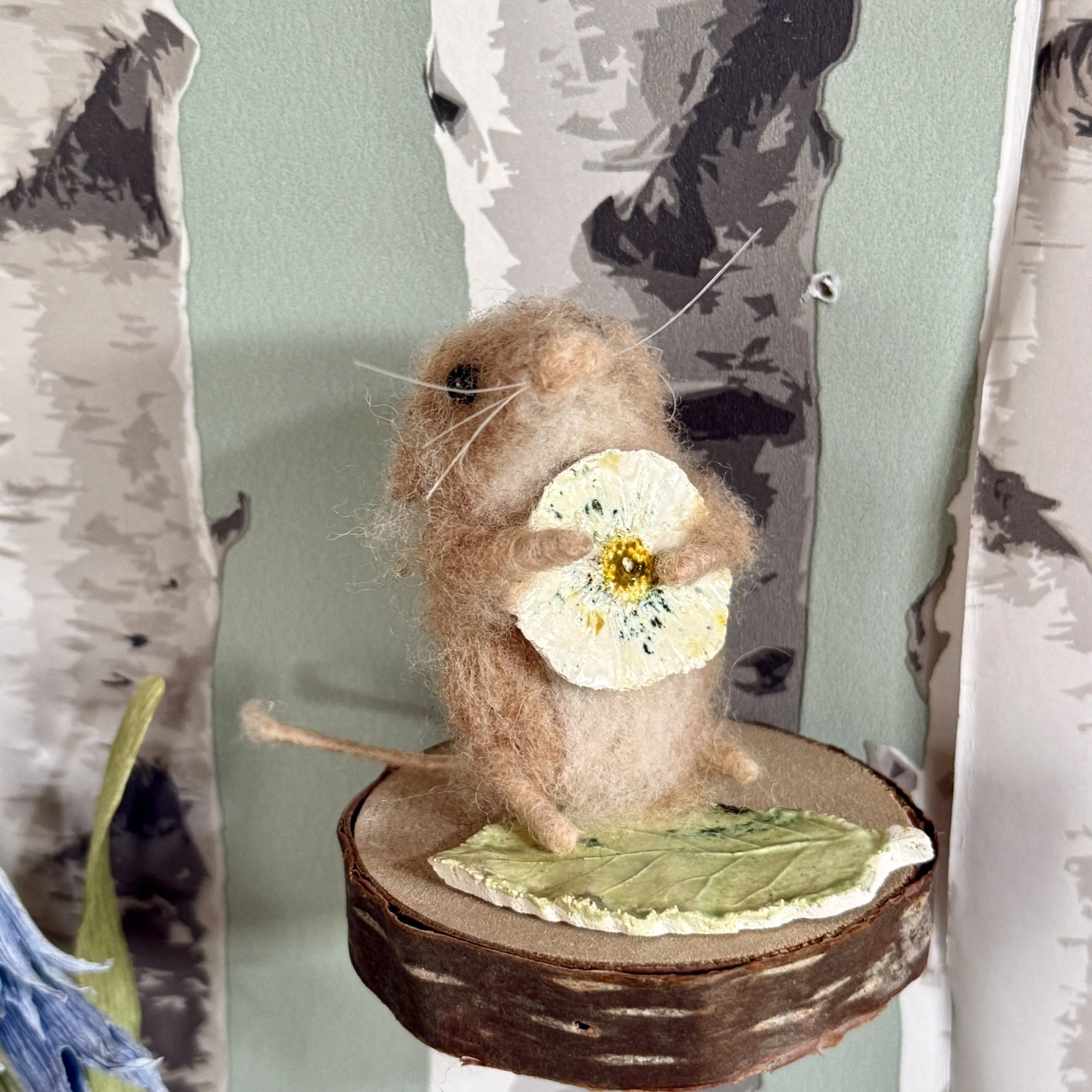 Little dormouse with a ceramic cast of a daisy flower, standing on a ceramic leaf. Dormouse is approx 6cm tall and can be moved and posed as you wish. £130