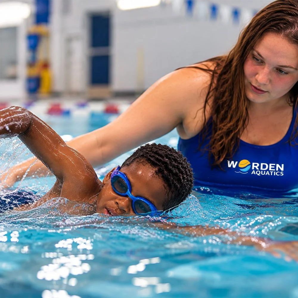 Coach Fiona of Worden Aquatics guides a young swimmer wearing blue goggles as he practices his freestyle stroke during a private swim lesson in Nashville, TN.