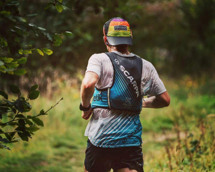 Tim running a forest trail wearing a race vest