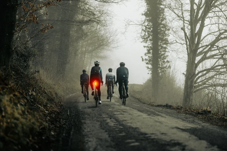 Group of cyclists riding a misty lane