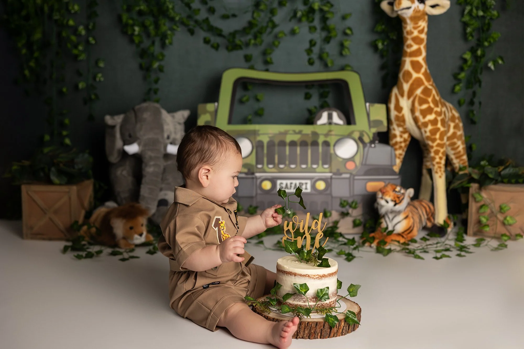 Baby boy playing with cake during safari themed cake smash session in Austin TX