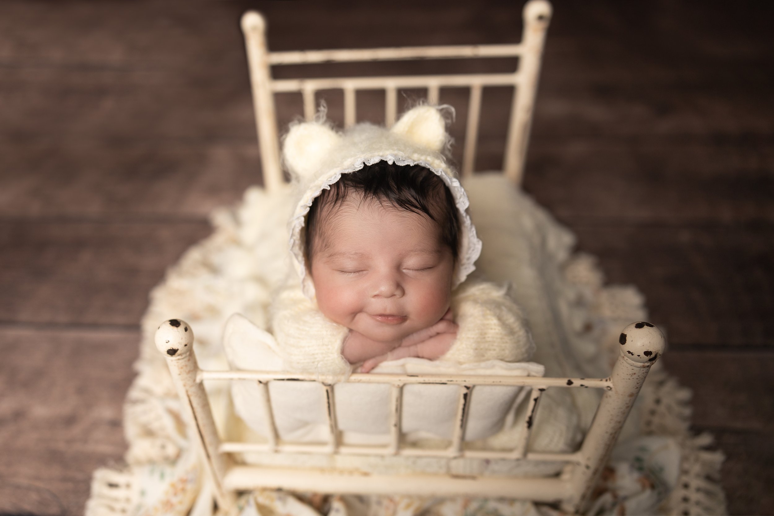 Sleeping newborn baby posed in a vintage bed during an in-home studio newborn photography session in Austin, Texas.