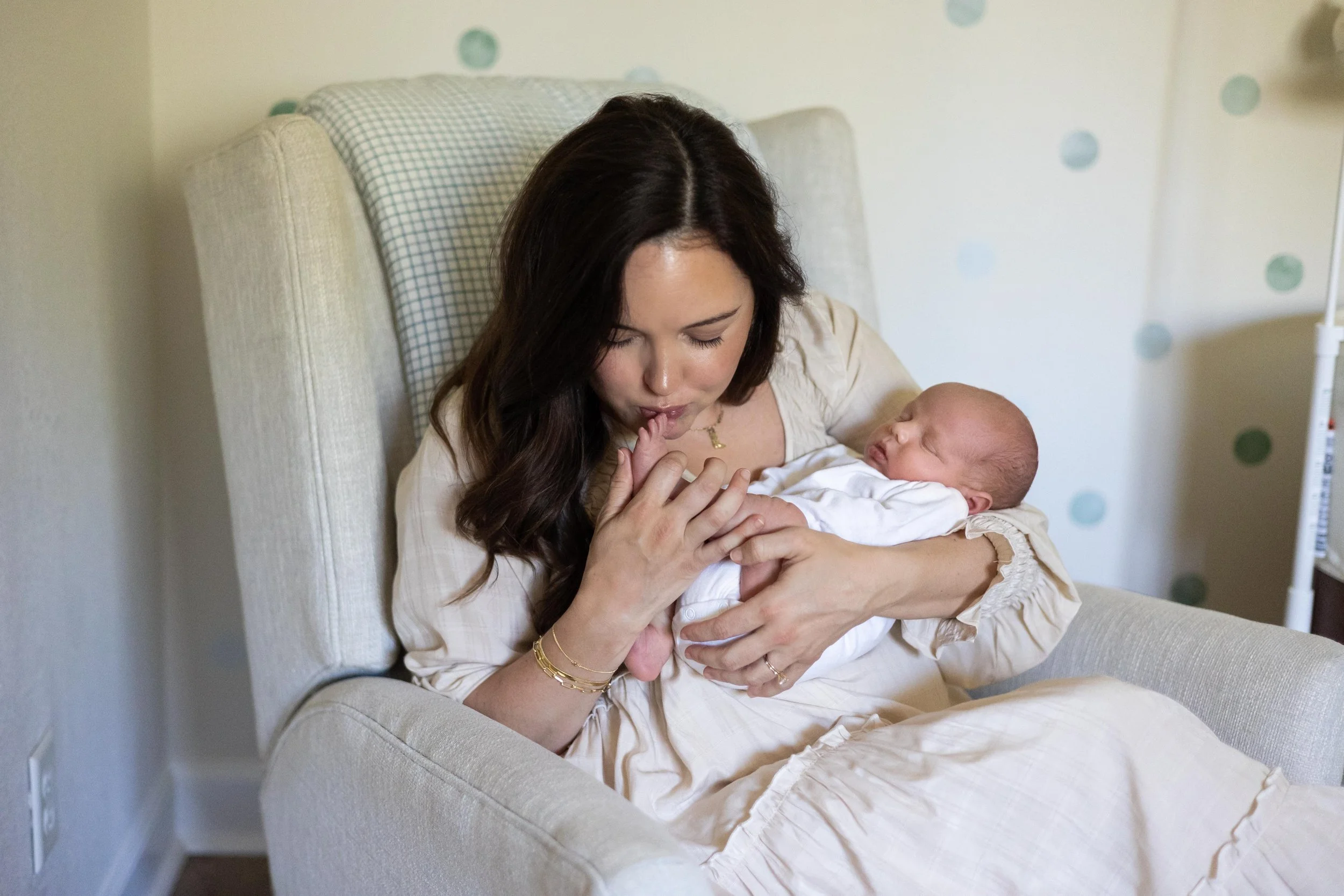 Mother kissing her newborn baby's foot during an in-home newborn photography session in Austin, Texas.