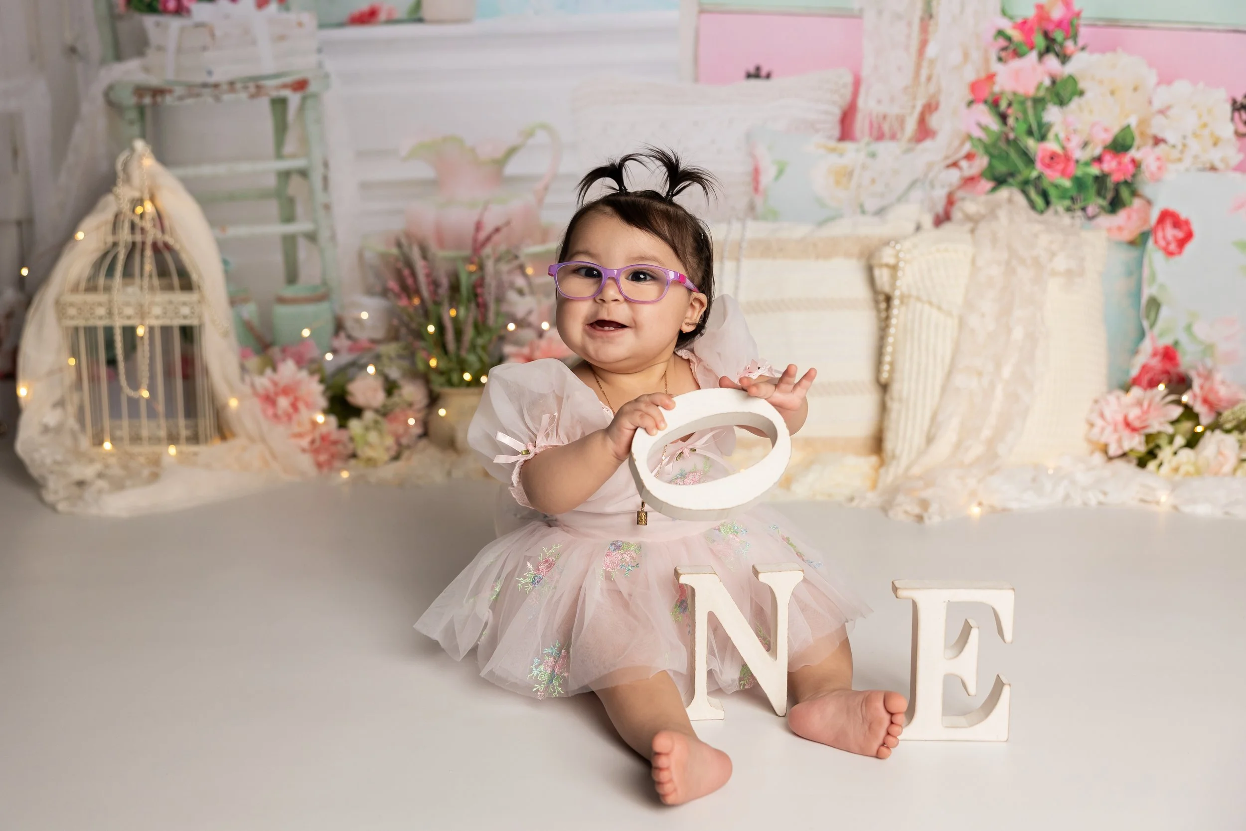 baby girl playing with one blocks on a frilly pink background