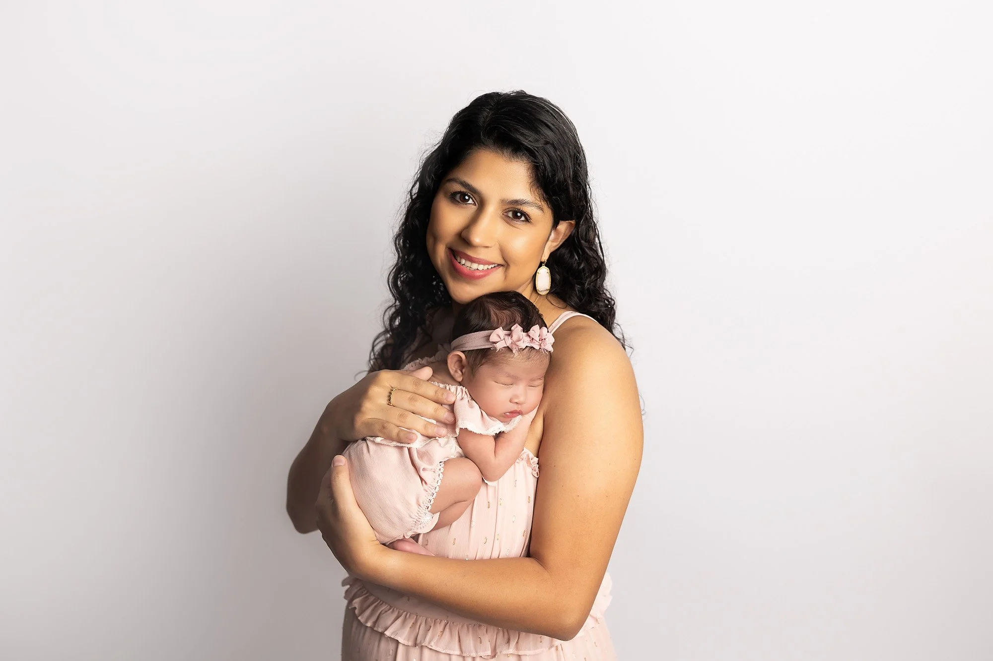 mom holding newborn girl and smiling for the camera