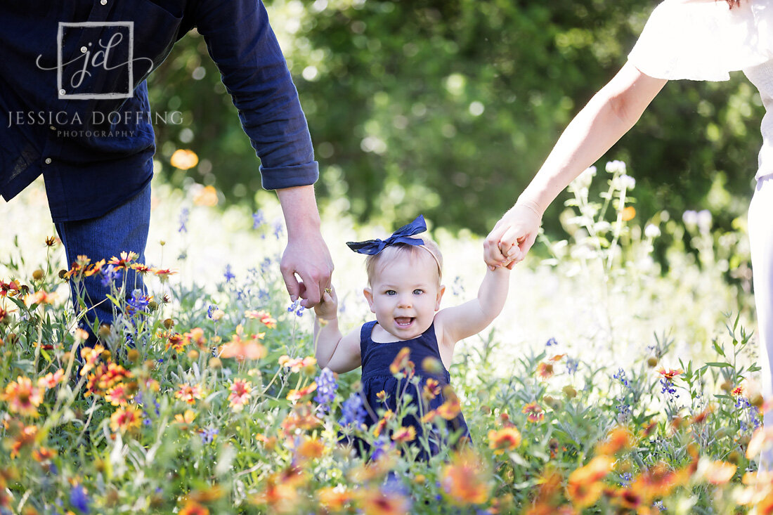 baby girl parents hands wildflowers