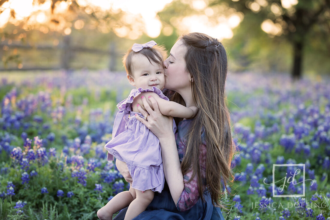 mom kissing daughter bluebonnets