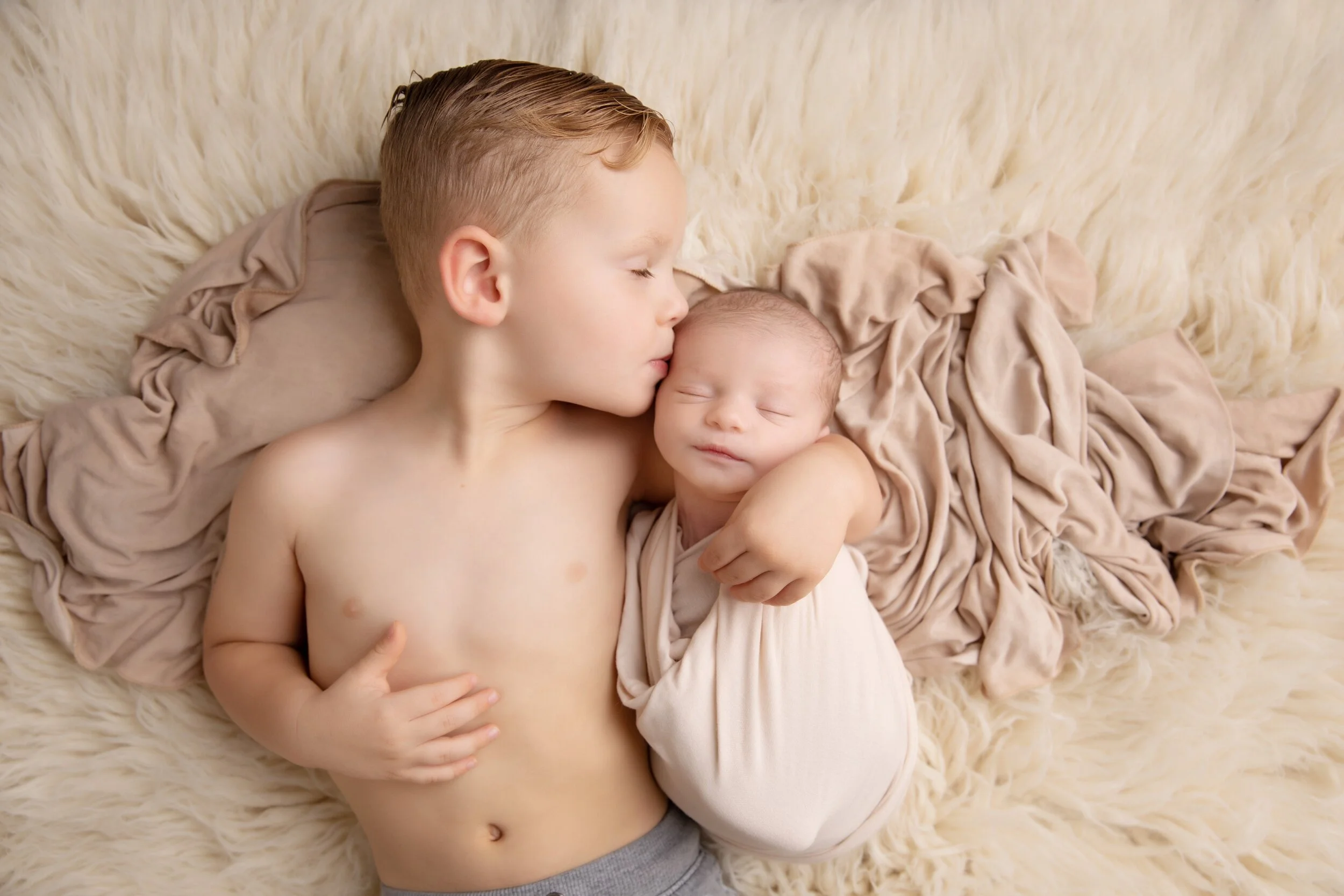 Older brother kissing newborn baby Porter during their Austin, Texas newborn photography session.