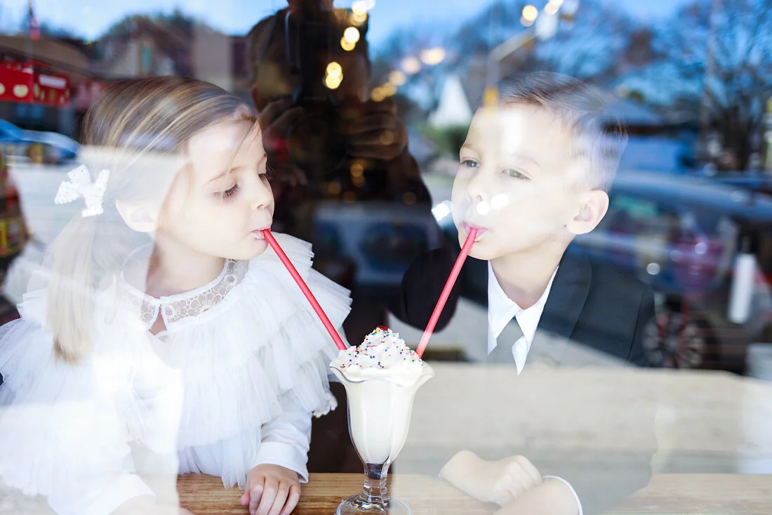 Two children sharing a milkshake at Big Top Candy Shop in Austin during a fun lifestyle photo session