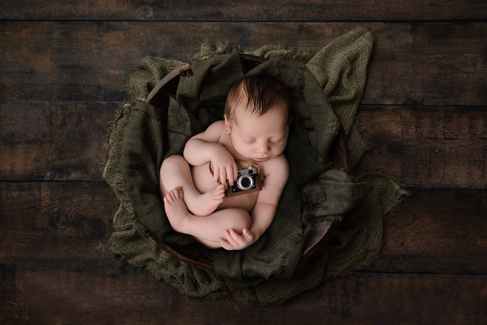 newborn boy holding tiny camera