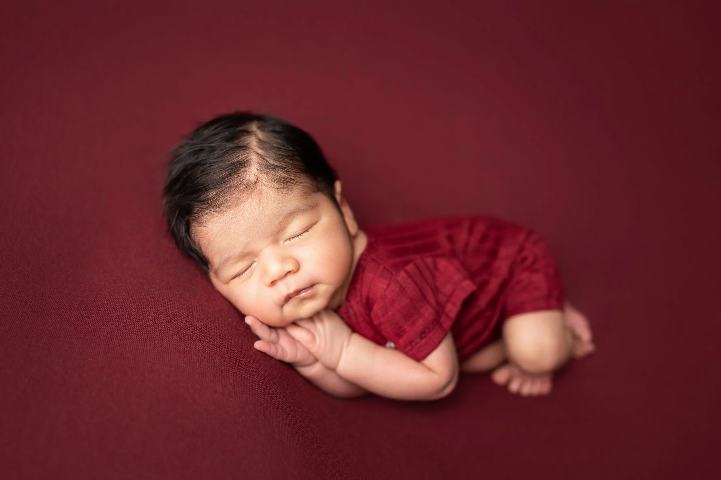 newborn-side-lying-pose-red-backdrop.jpg