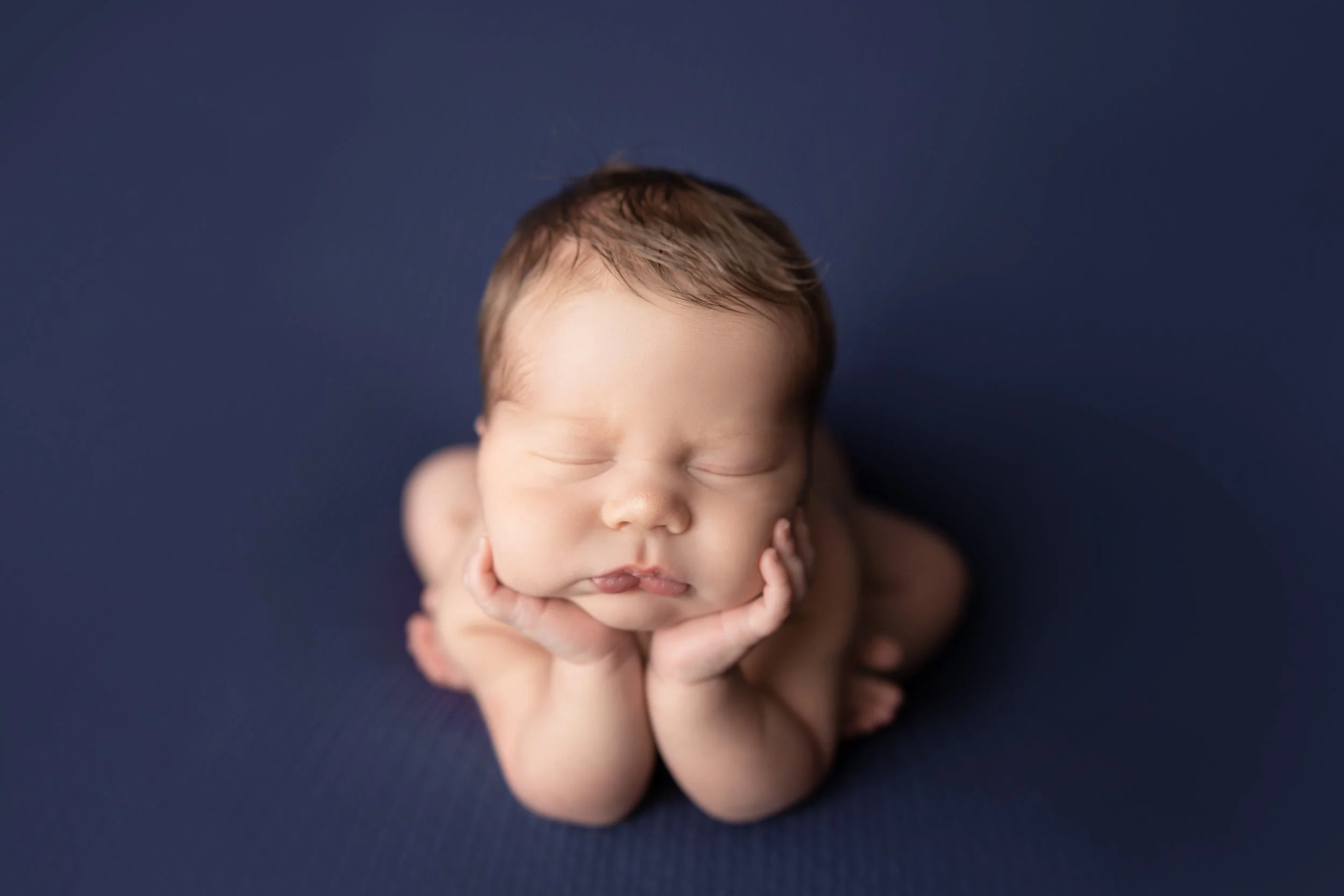 Sleeping newborn in the classic froggy pose, created safely using composite editing with continuous support throughout the session at an Austin newborn photography studio.