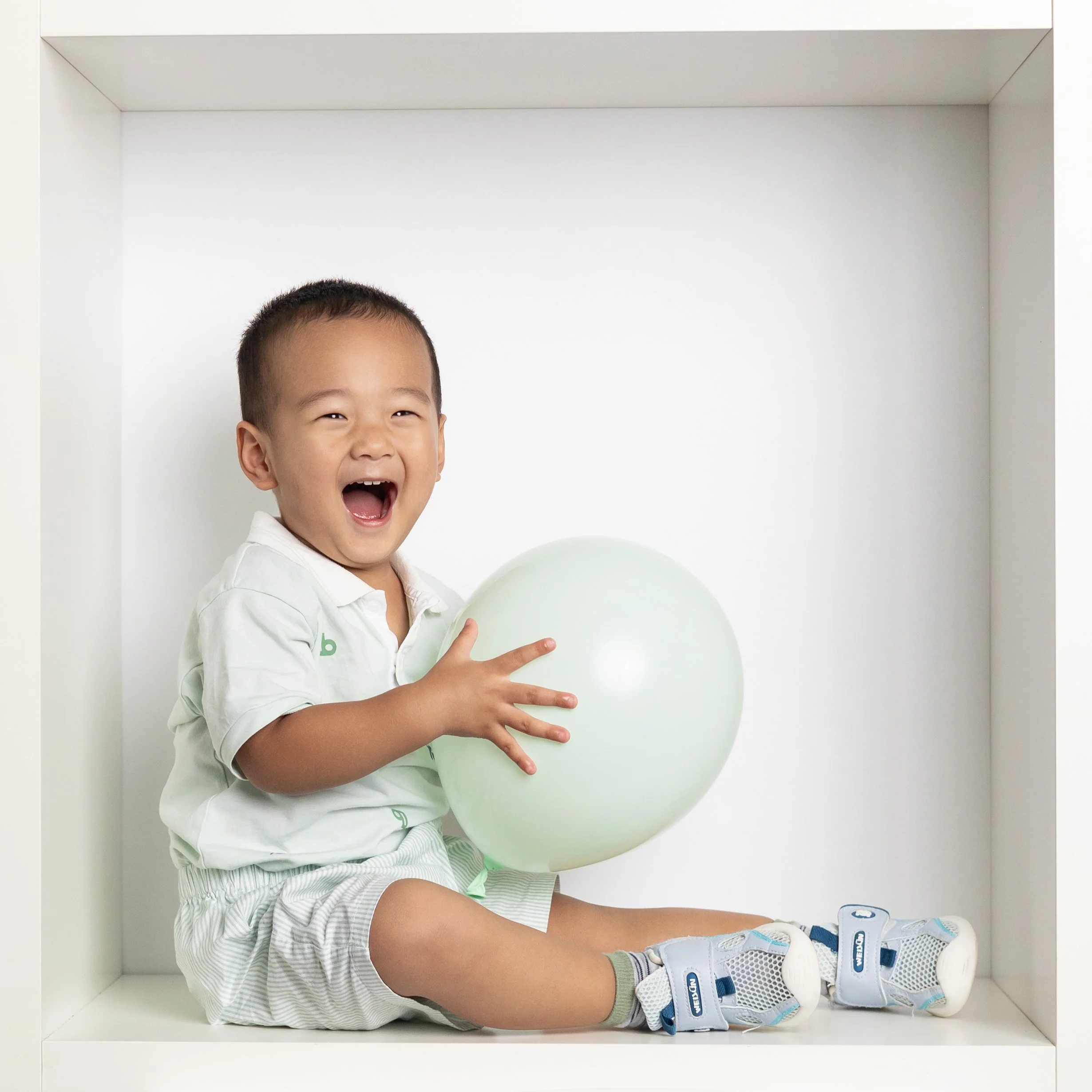  Toddler boy laughing and holding balloon for in-the-box mini session 