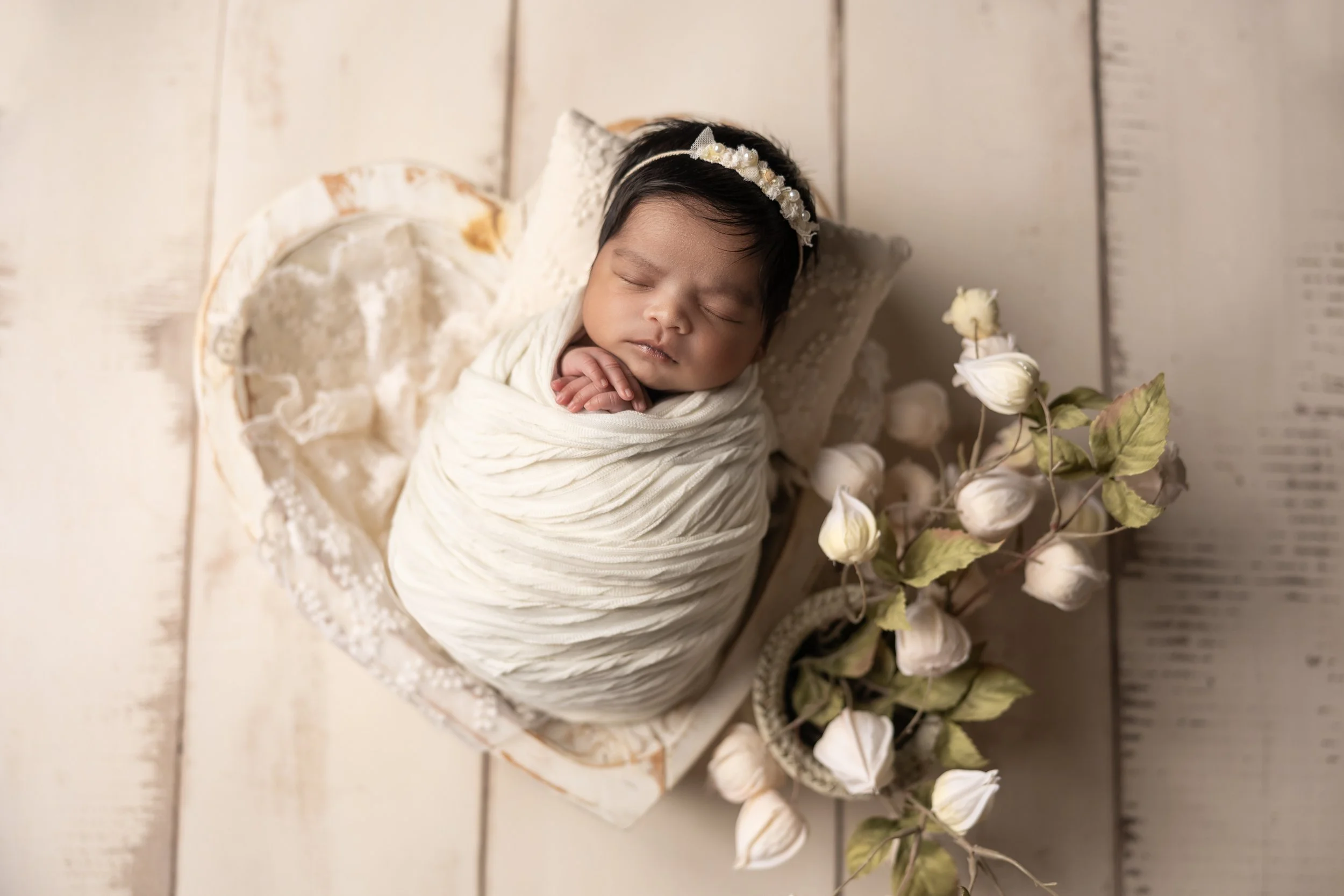 newborn posed in heart bowl with greenery neutral setup