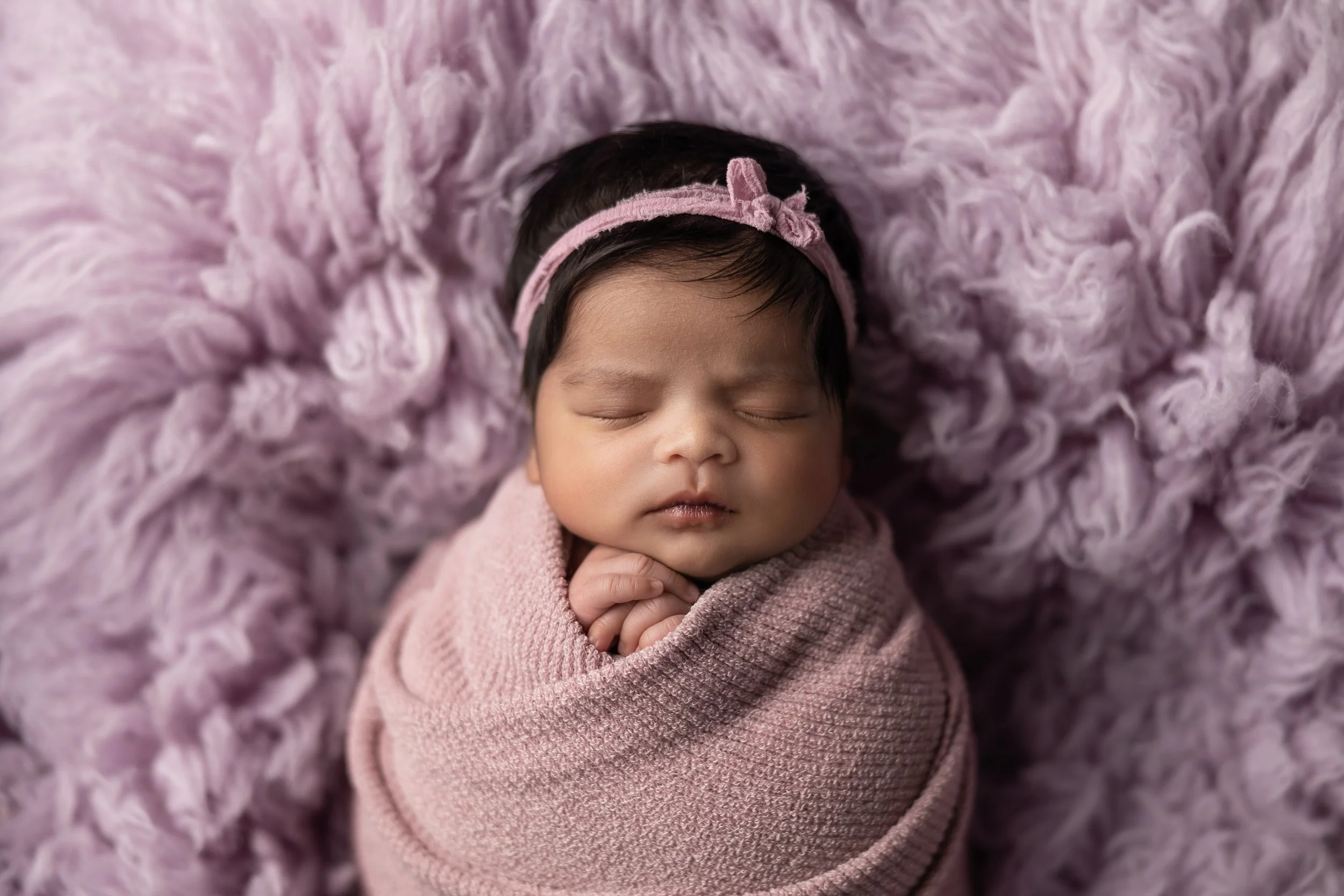 newborn swaddled in purple close-up 
