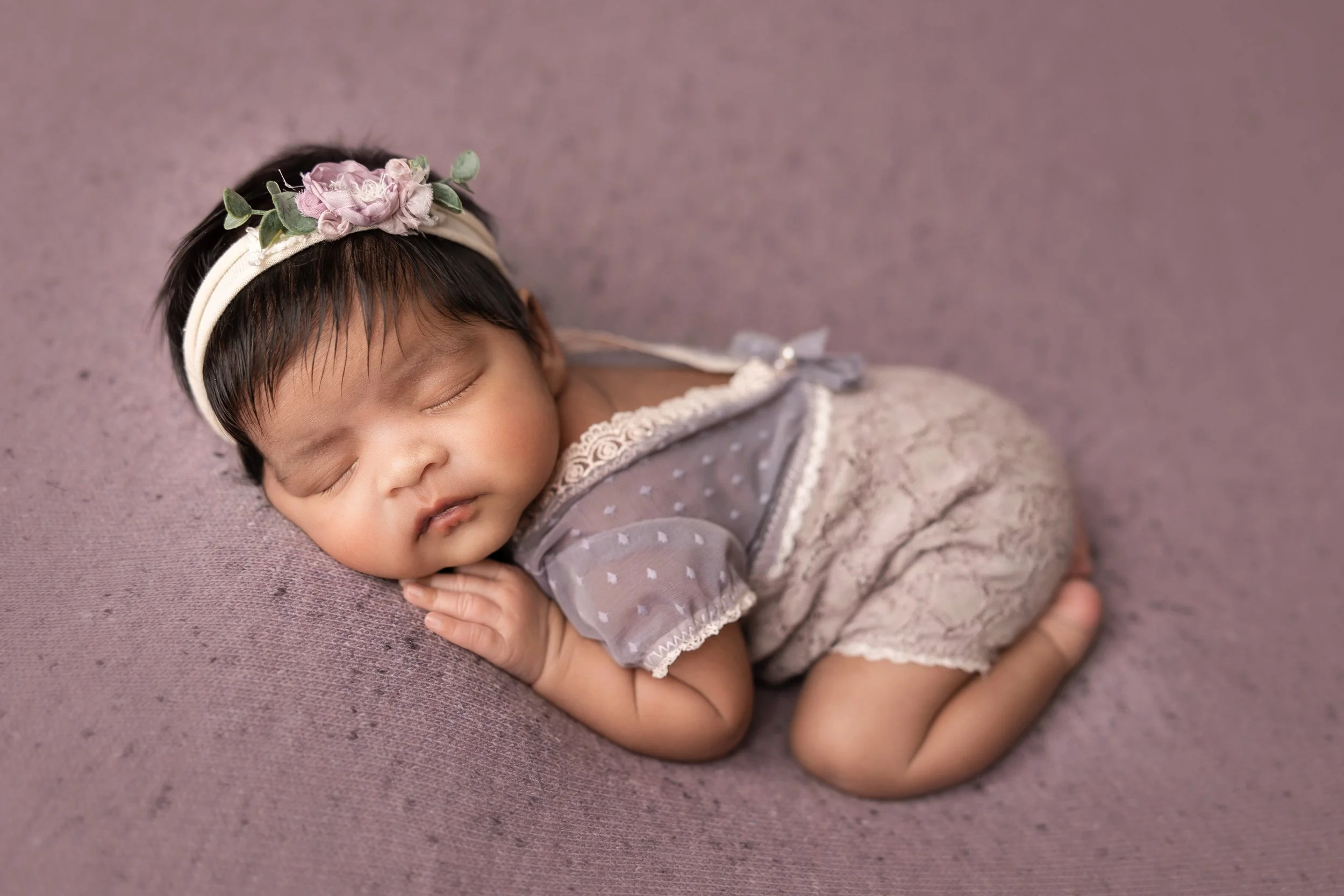 posed newborn lying on stomach with head turned