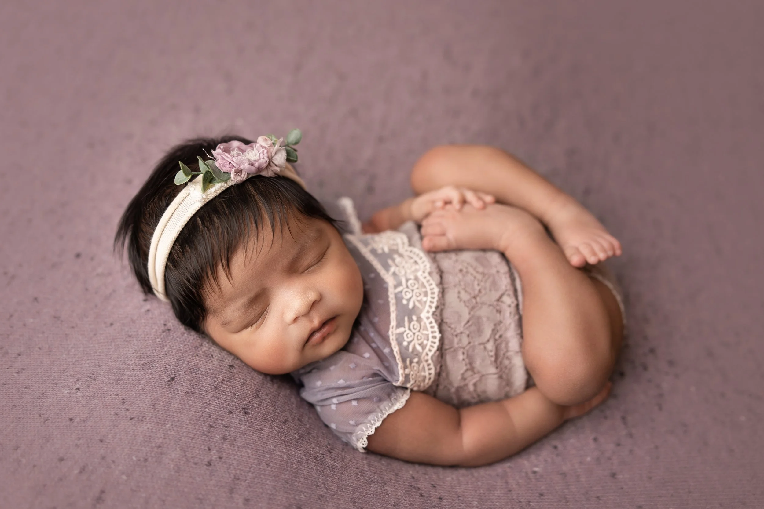 newborn curled pose on soft neutral backdrop