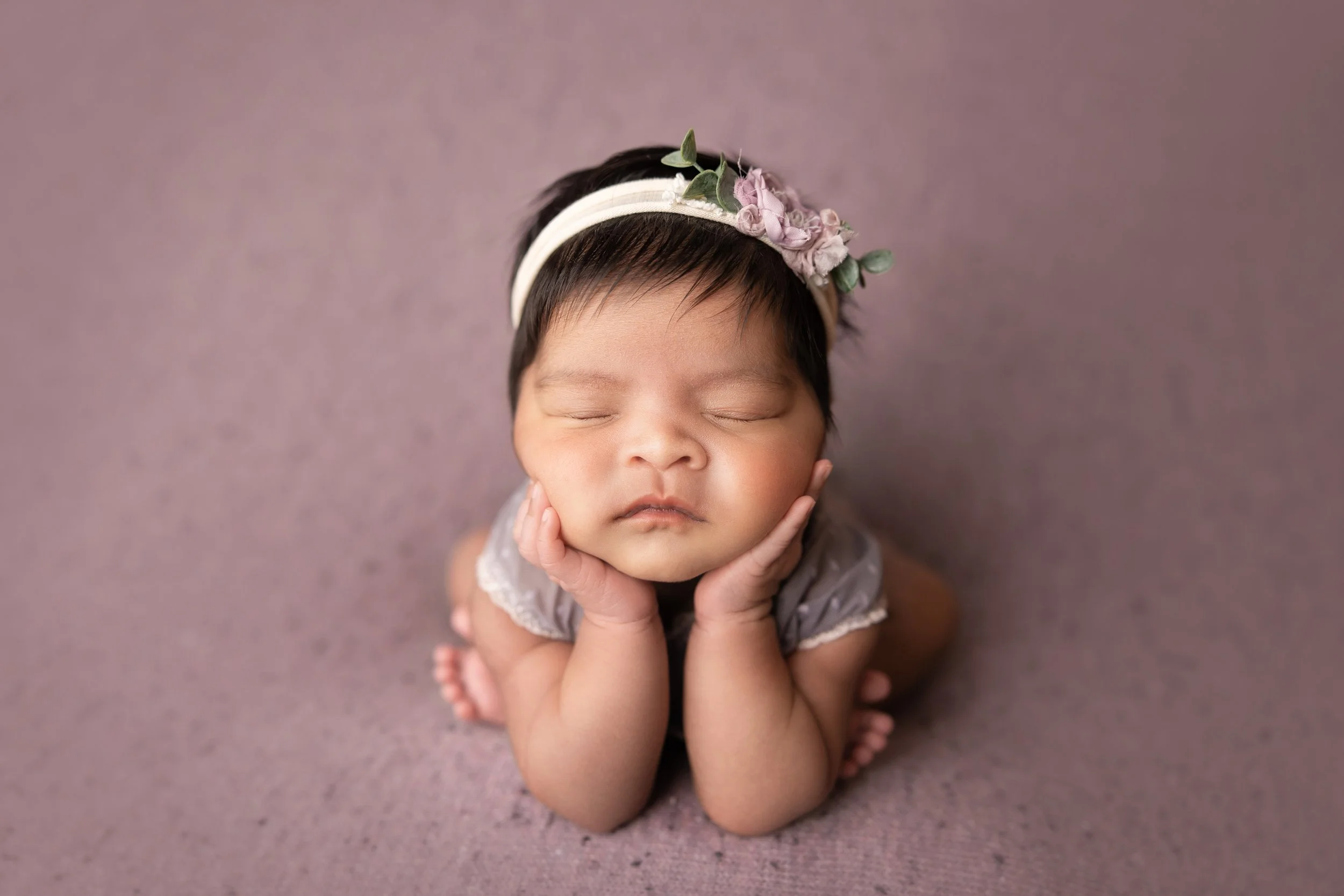 baby girl posed with head resting on hands