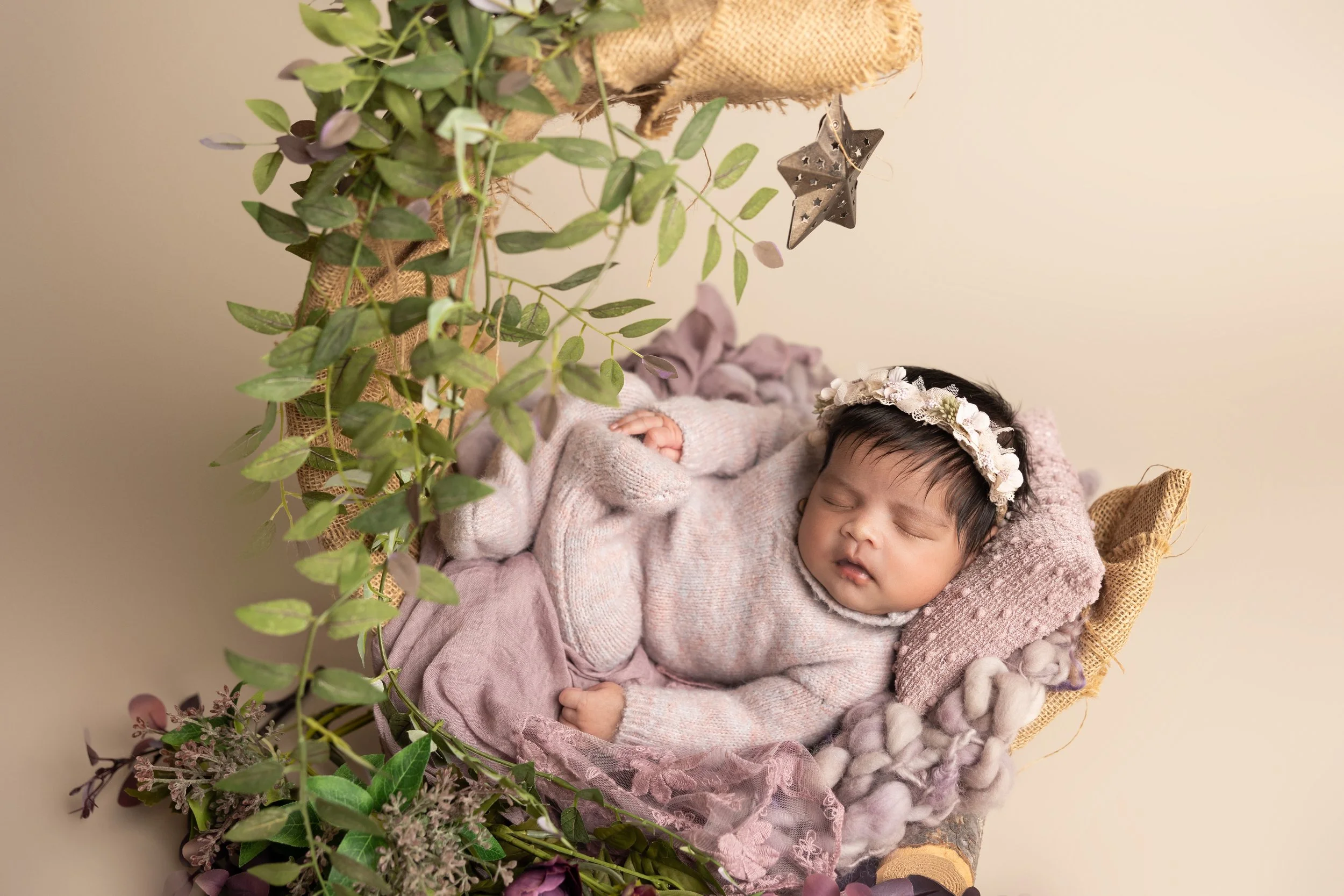 baby girl in crescent moon newborn setup with soft tones