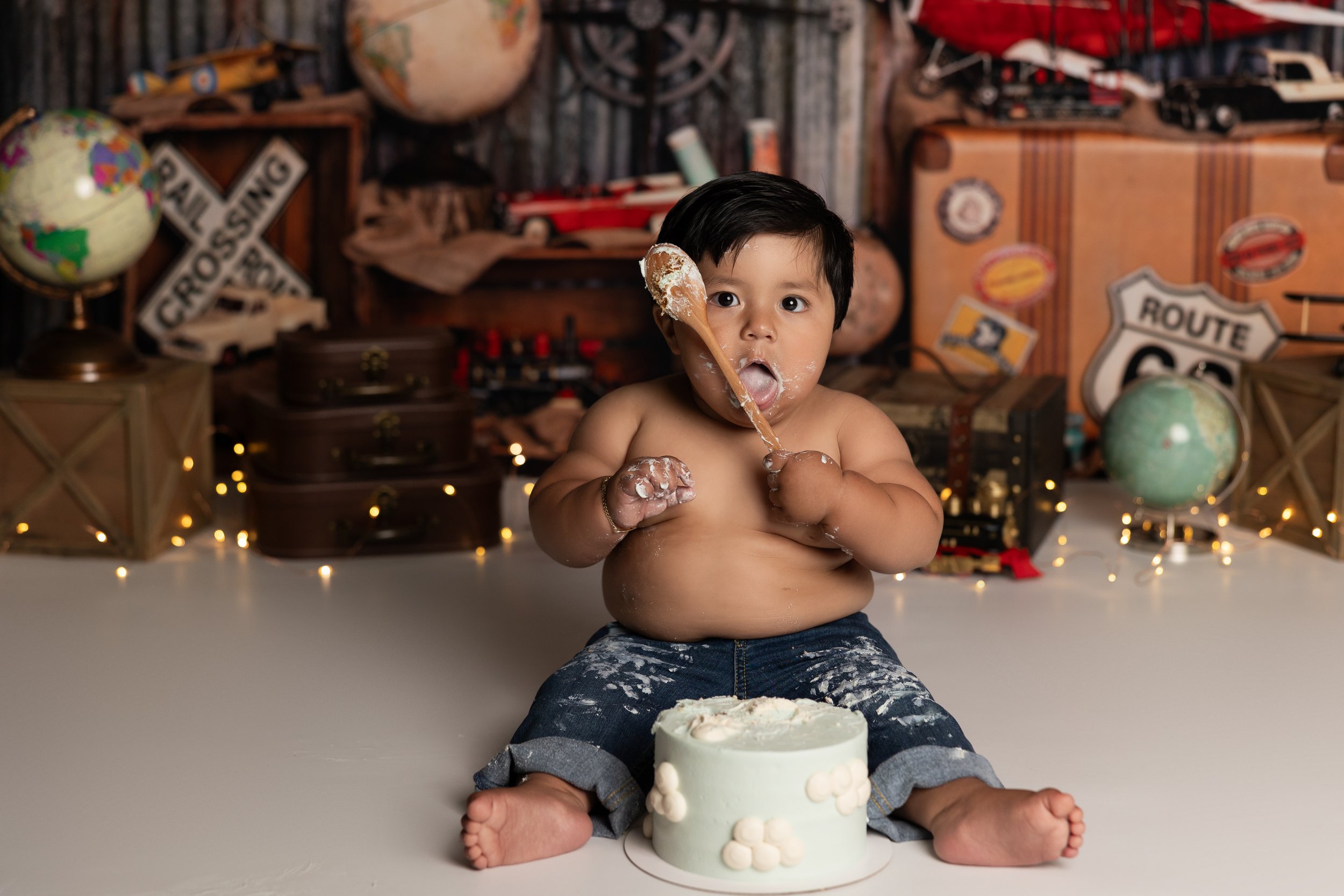 Vintage travel-themed cake smash session with custom birthday cake and adventure-inspired decor.