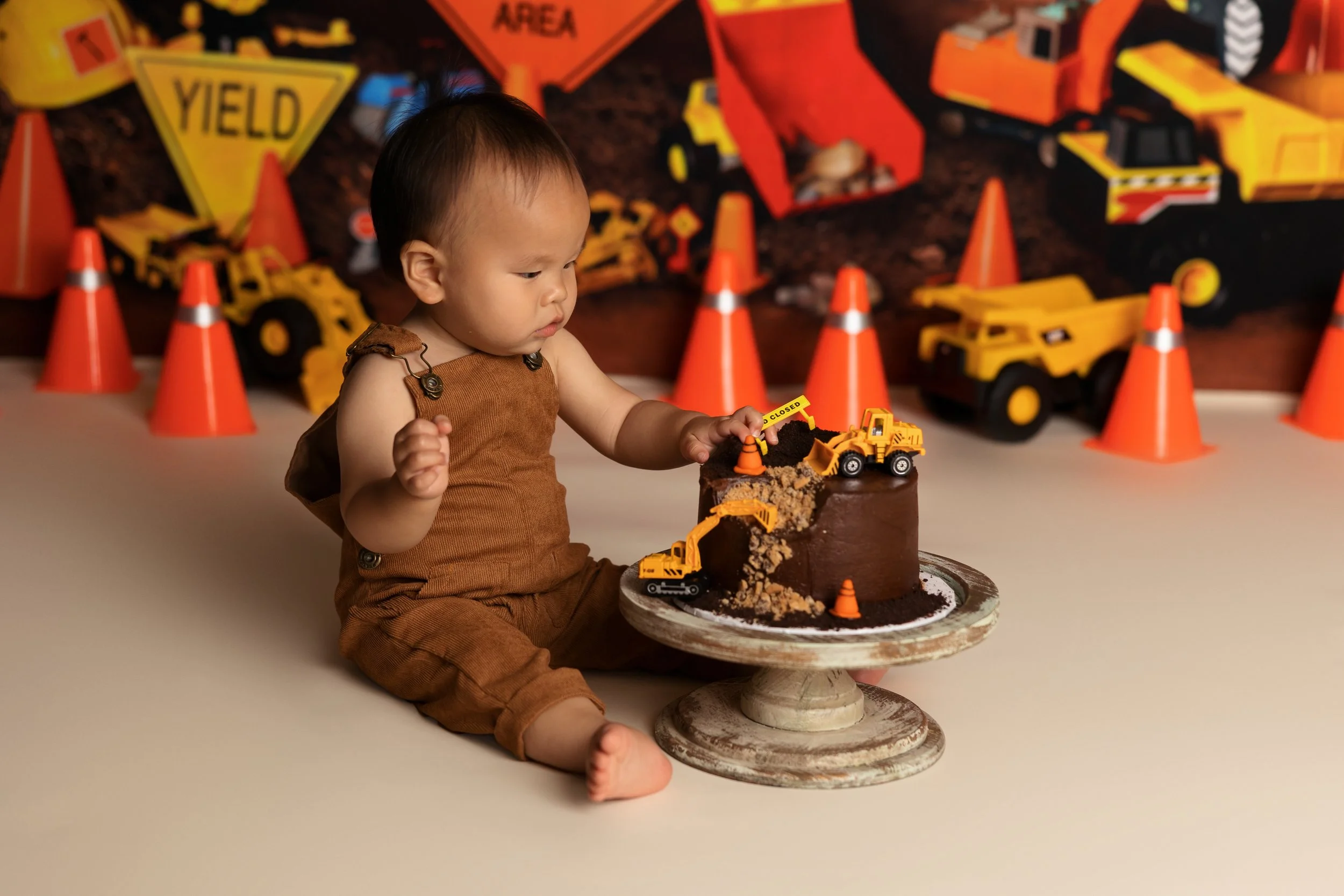 Construction cake smash – first birthday boy with chocolate cake and toy trucks