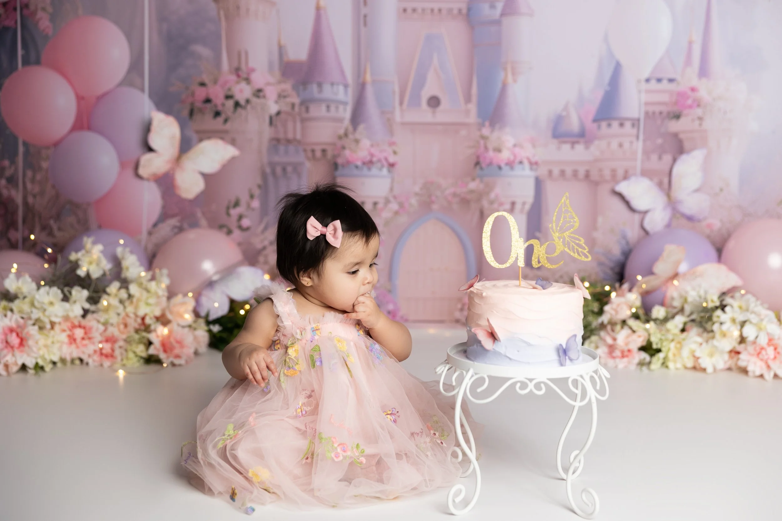 Princess cake smash – first birthday girl with soft pink cake and castle backdrop