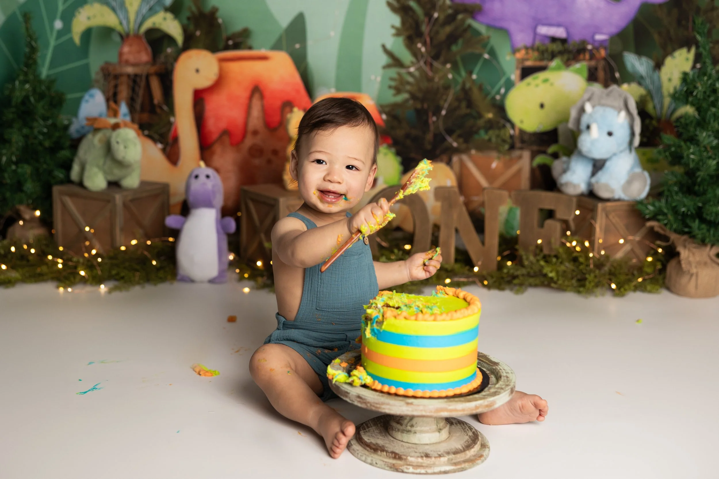 Dinosaur cake smash – first birthday boy with colorful dinosaur cake