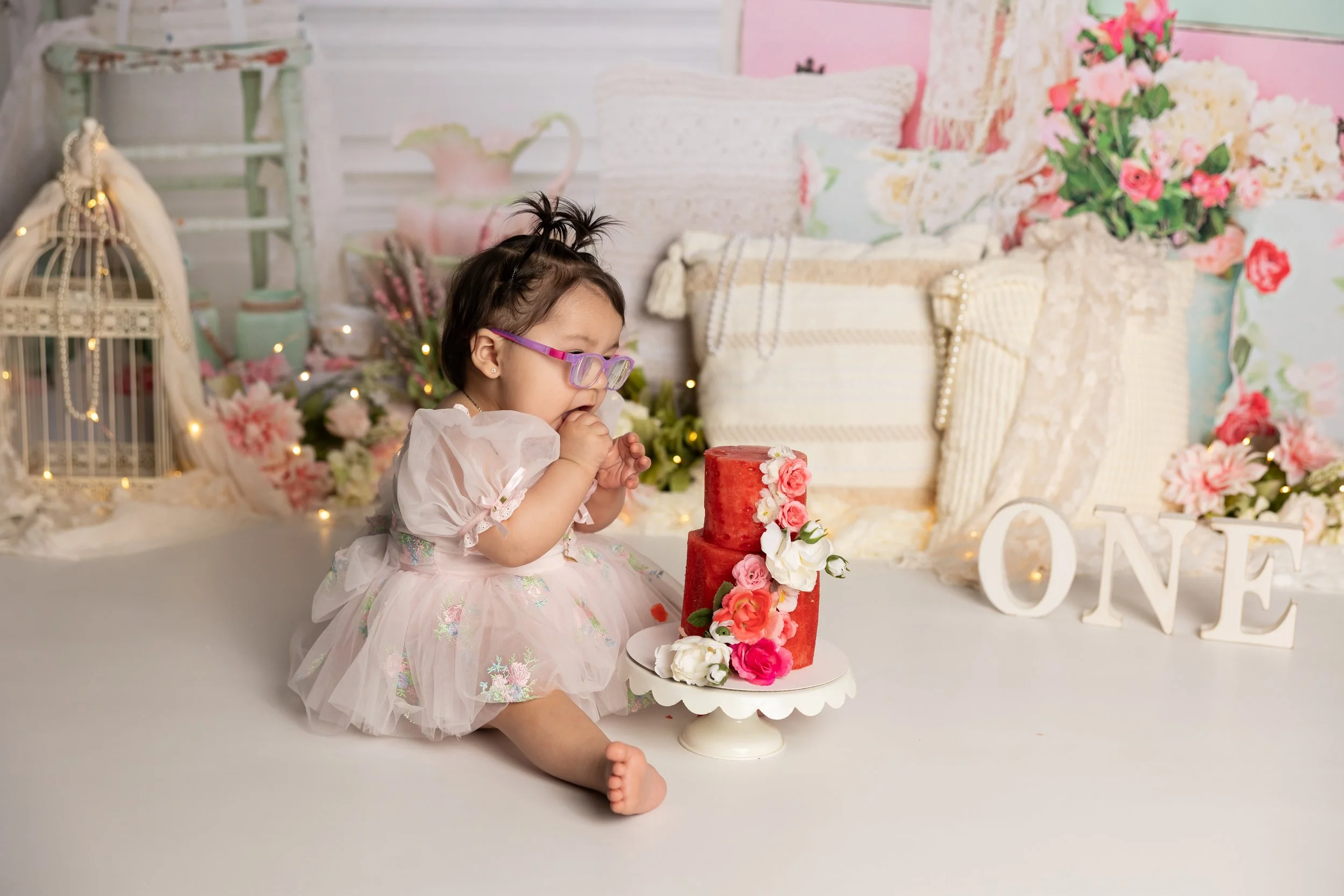 Baby girl tasting watermelon smash during first birthday session Austin
