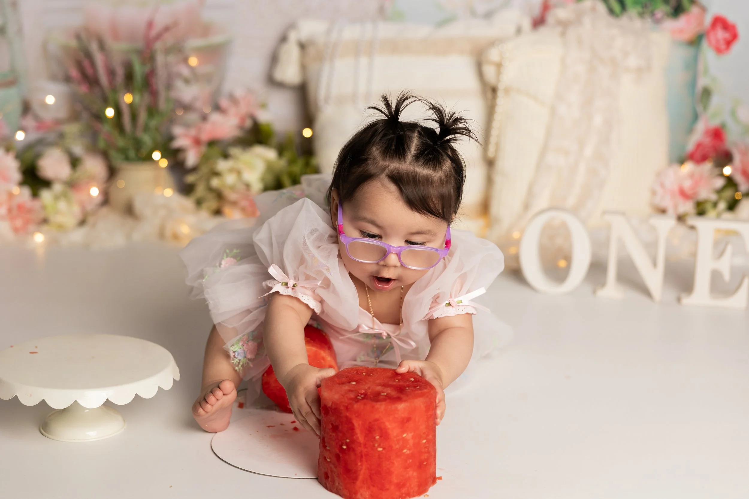Baby smashing watermelon cake during first birthday photoshoot Austin