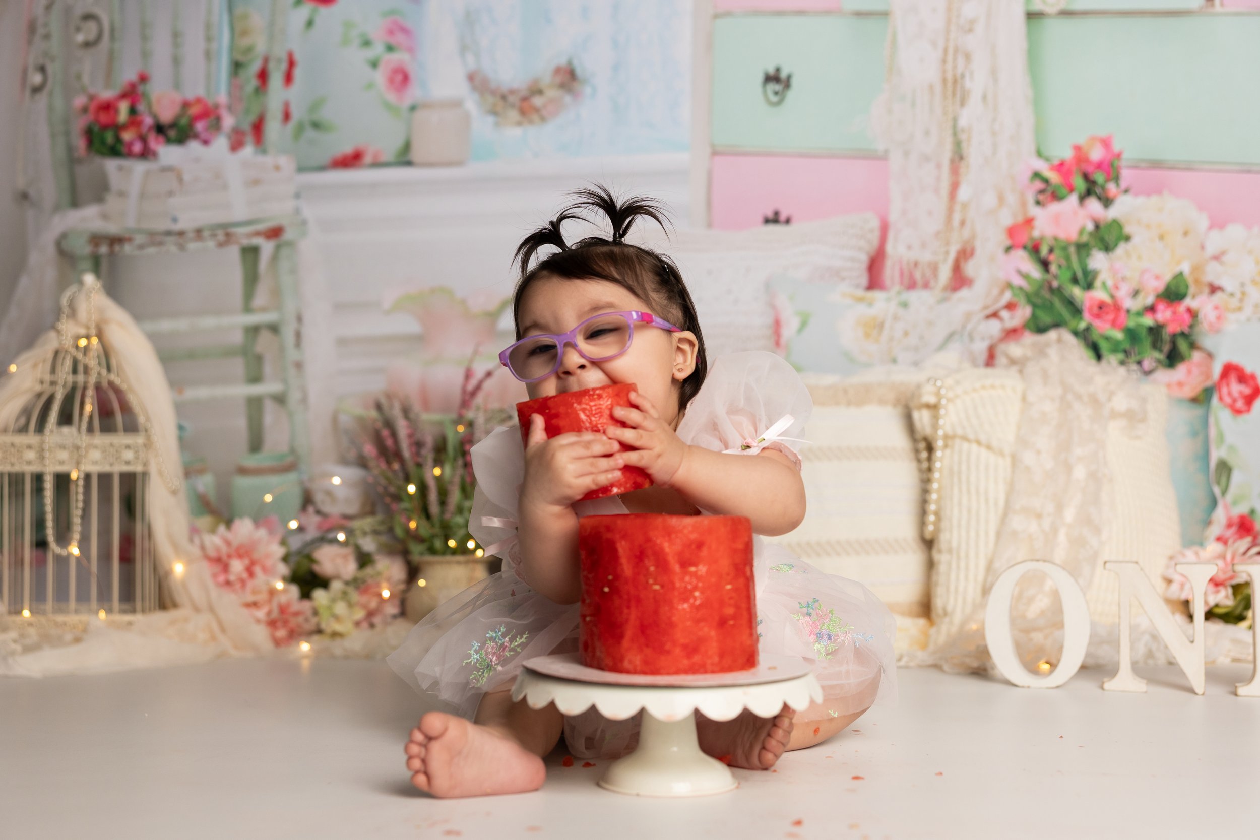 Baby girl biting watermelon during smash session Austin first birthday