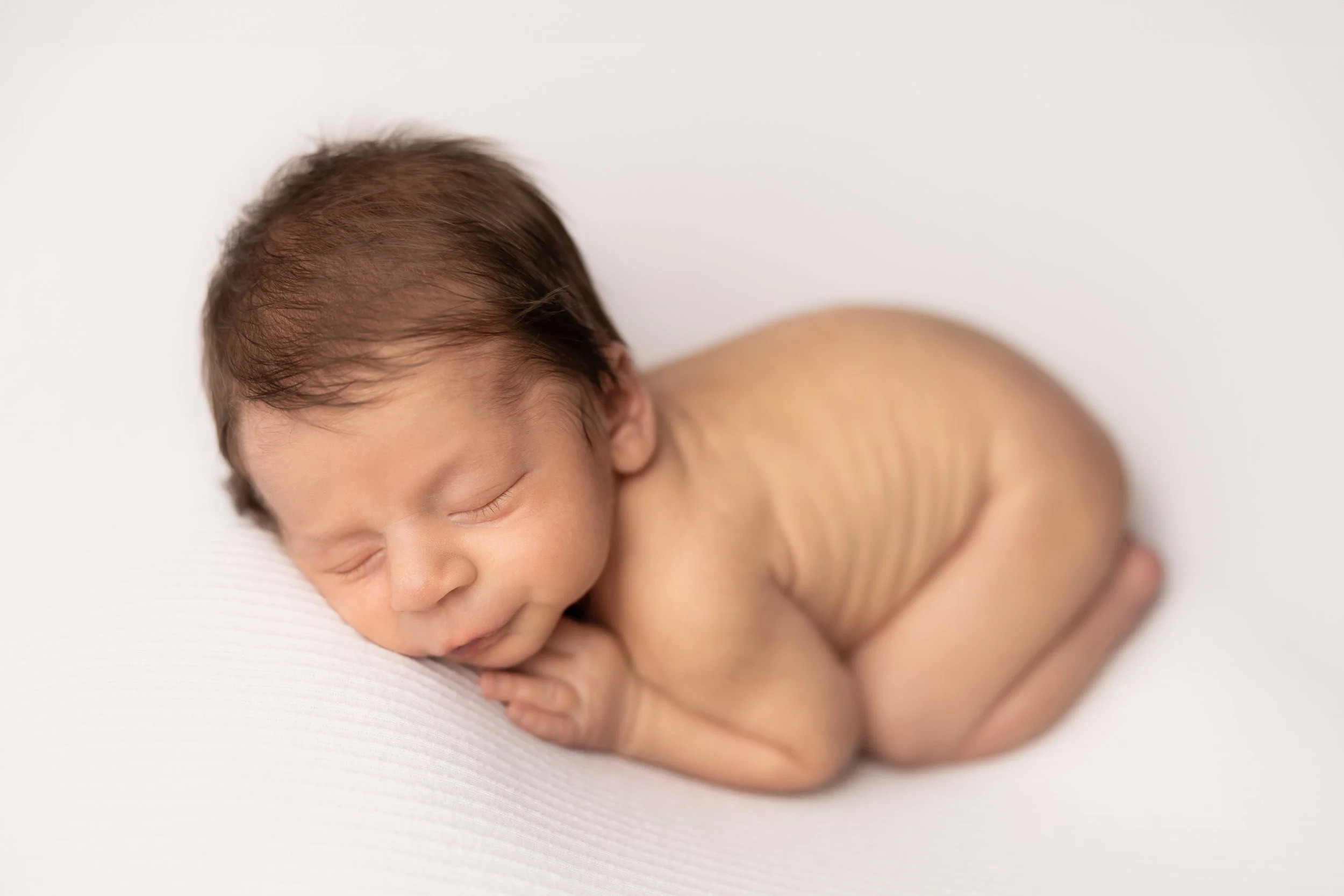 newborn baby boysleeping on soft white blanket