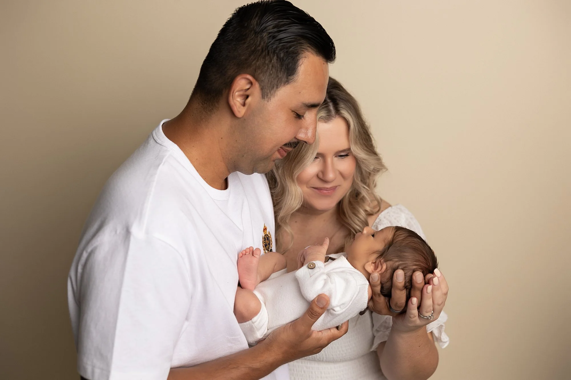 father holding newborn baby and looking down with calm expression