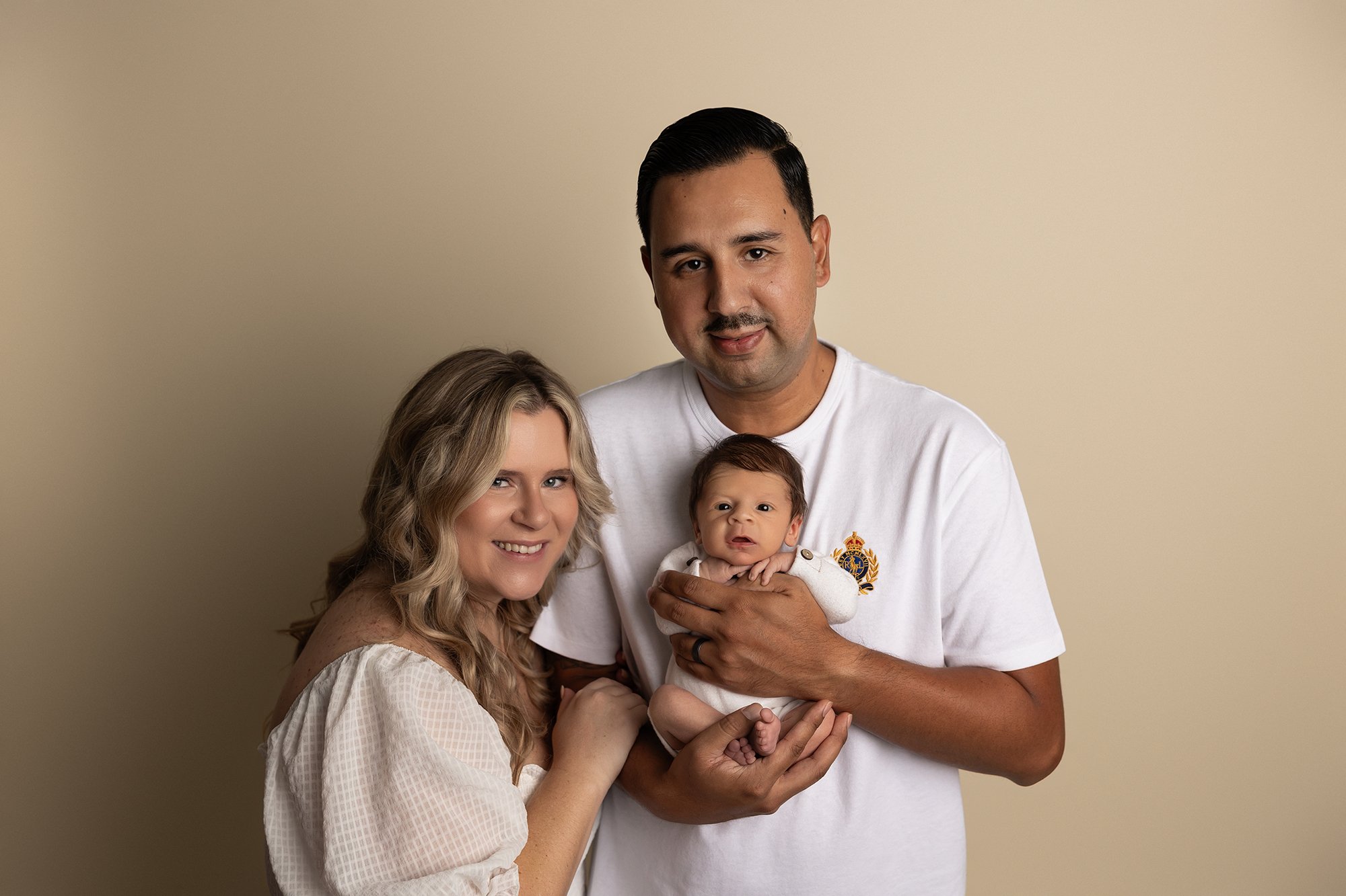 mother and father holding newborn baby and smiling at camera
