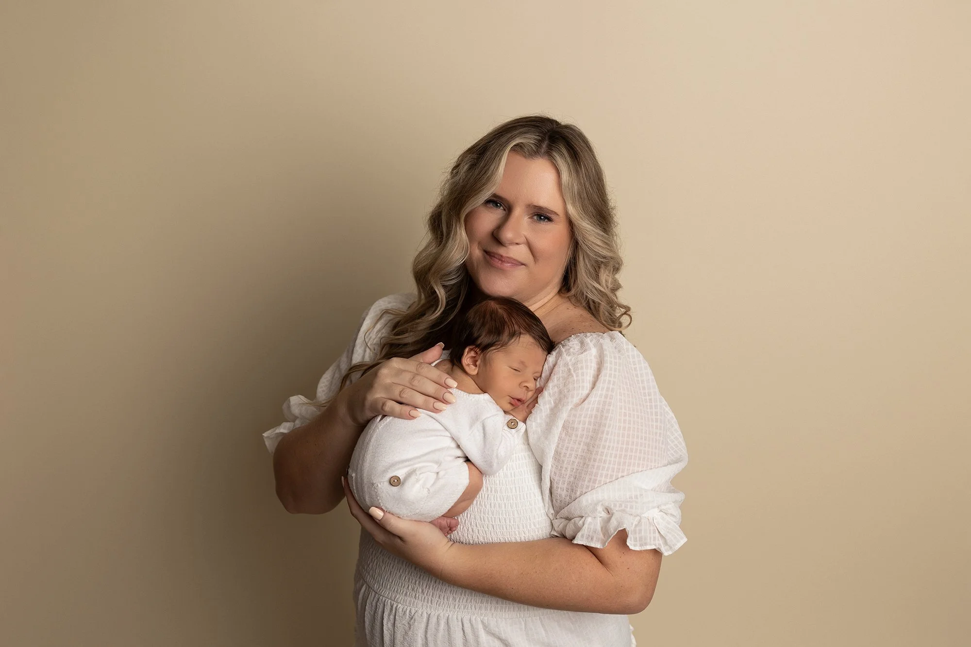 mother holding newborn baby in soft neutral portrait with warm expression