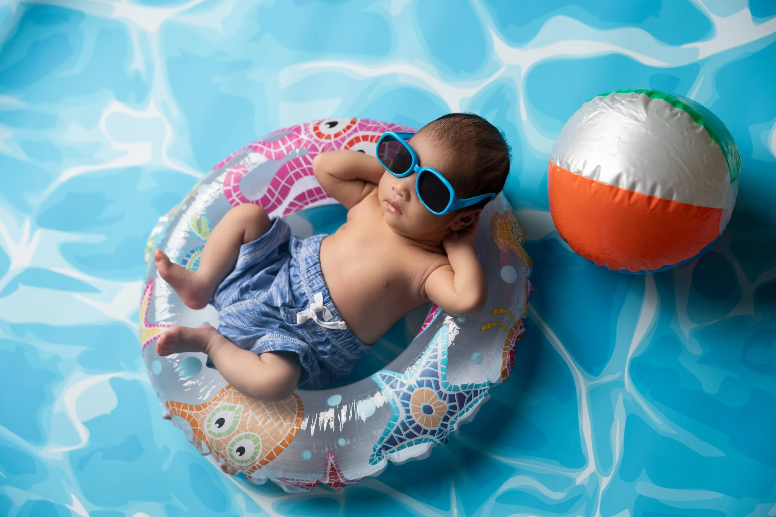 Summer newborn in pool float with sunglasses