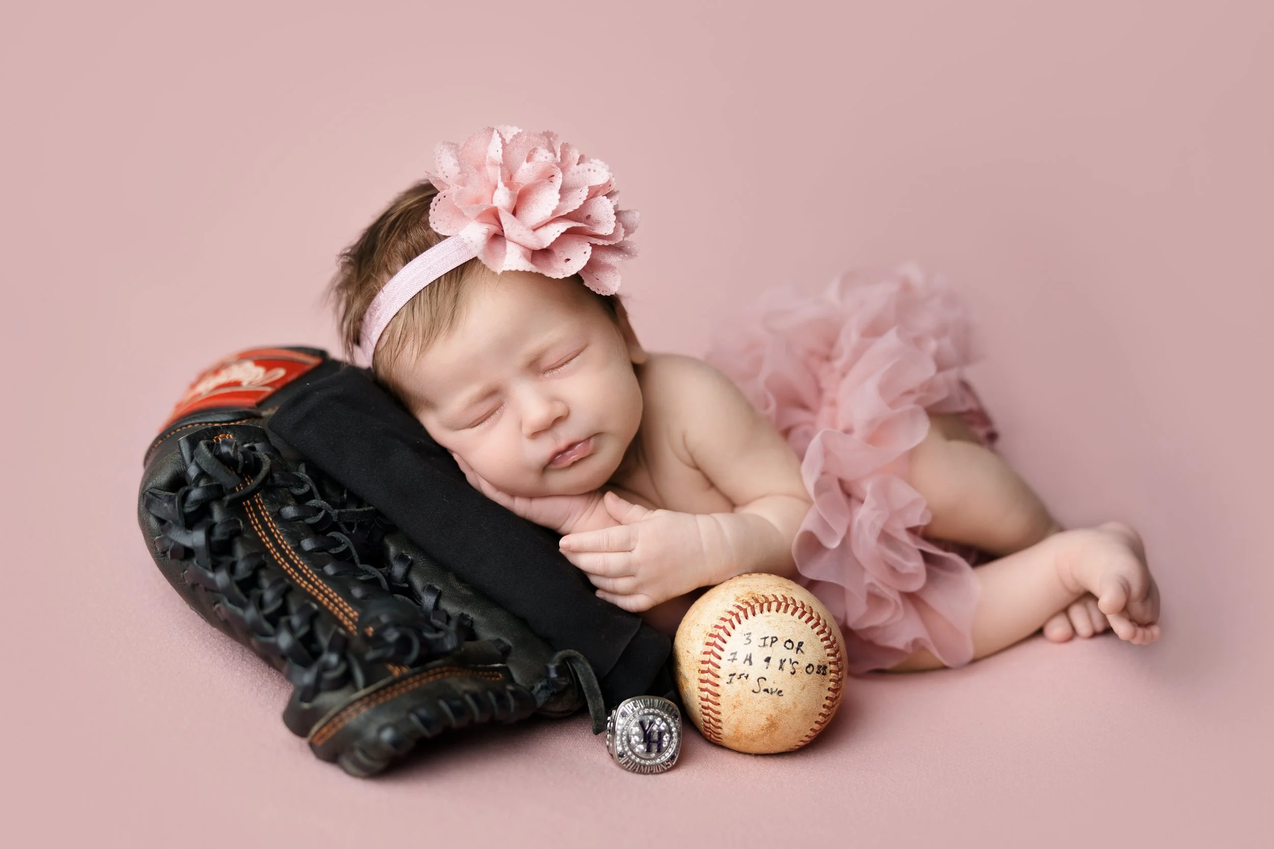 Baby girl posed with baseball glove and soft pink styling