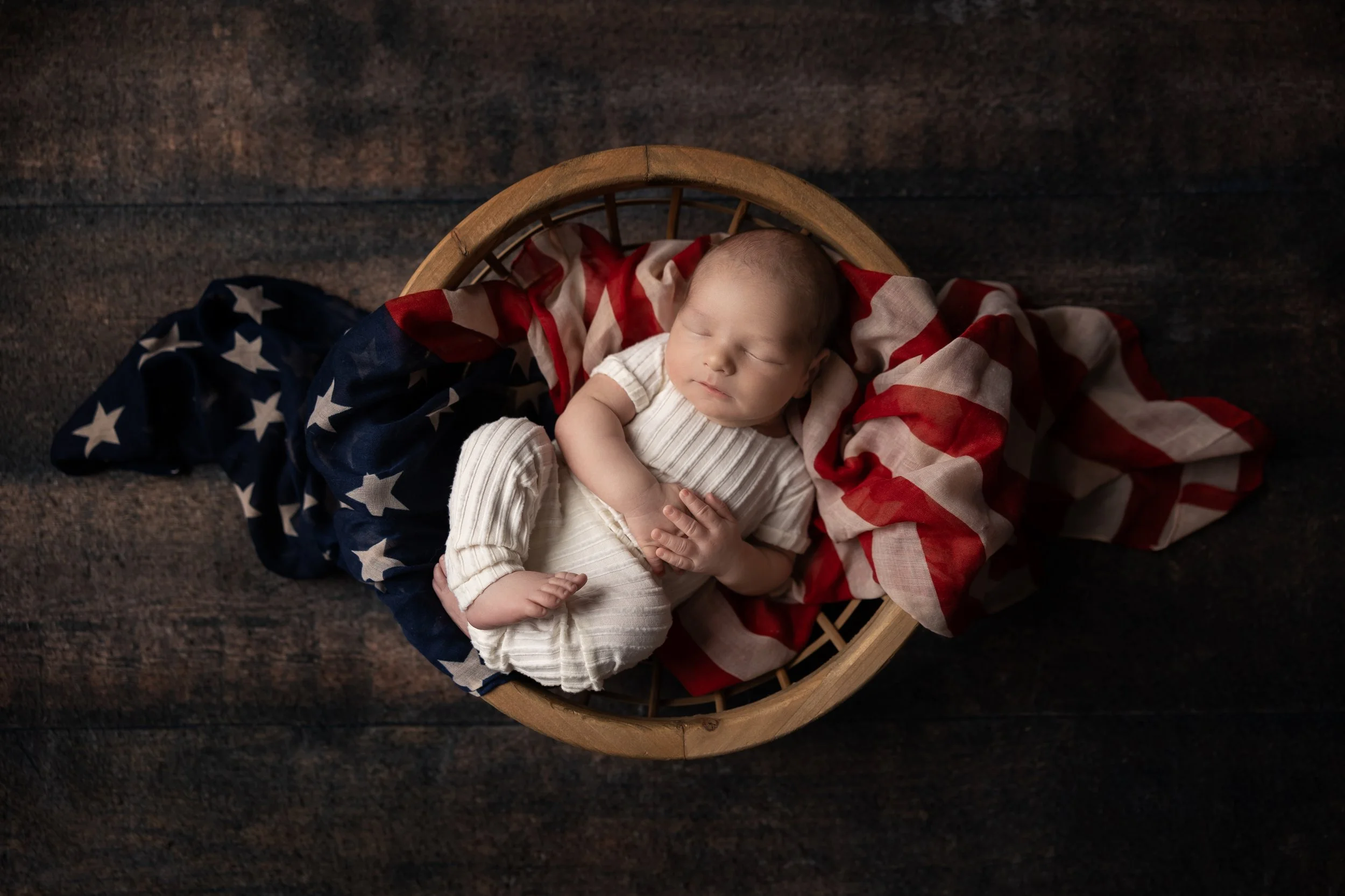 Newborn wrapped in American flag 4th of July setup