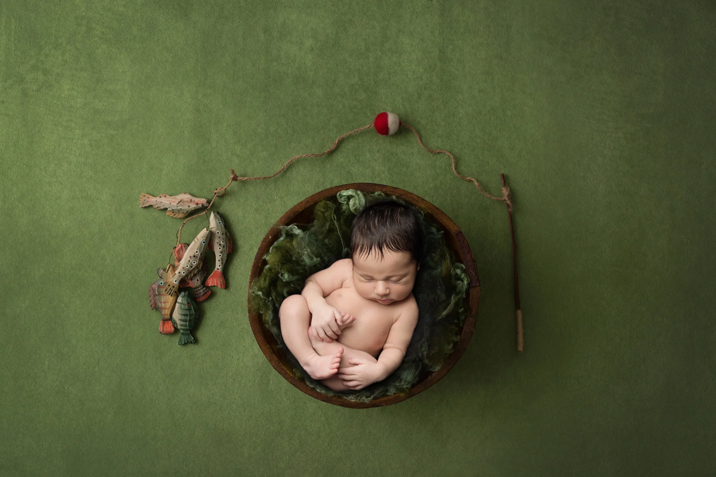 Baby posed in fishing bowl with green backdrop