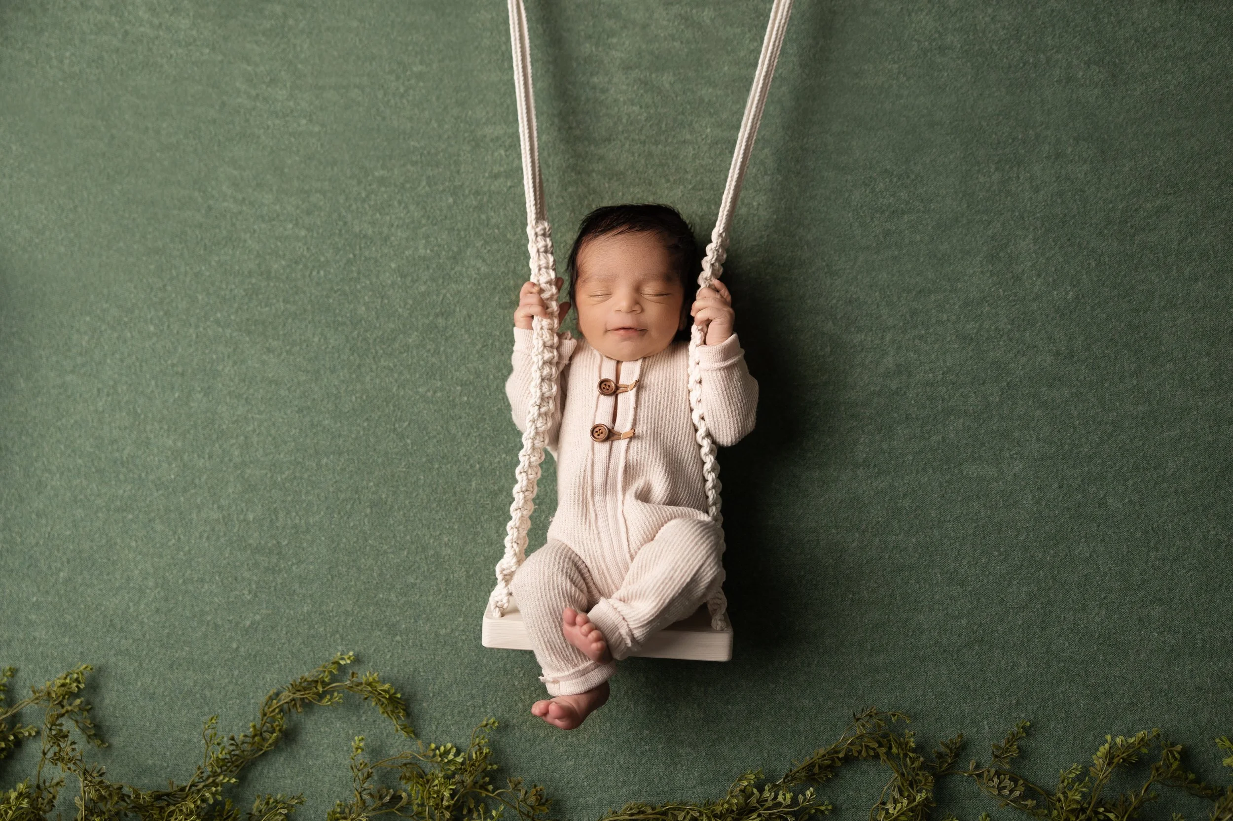 Baby in neutral outfit on simple studio swing