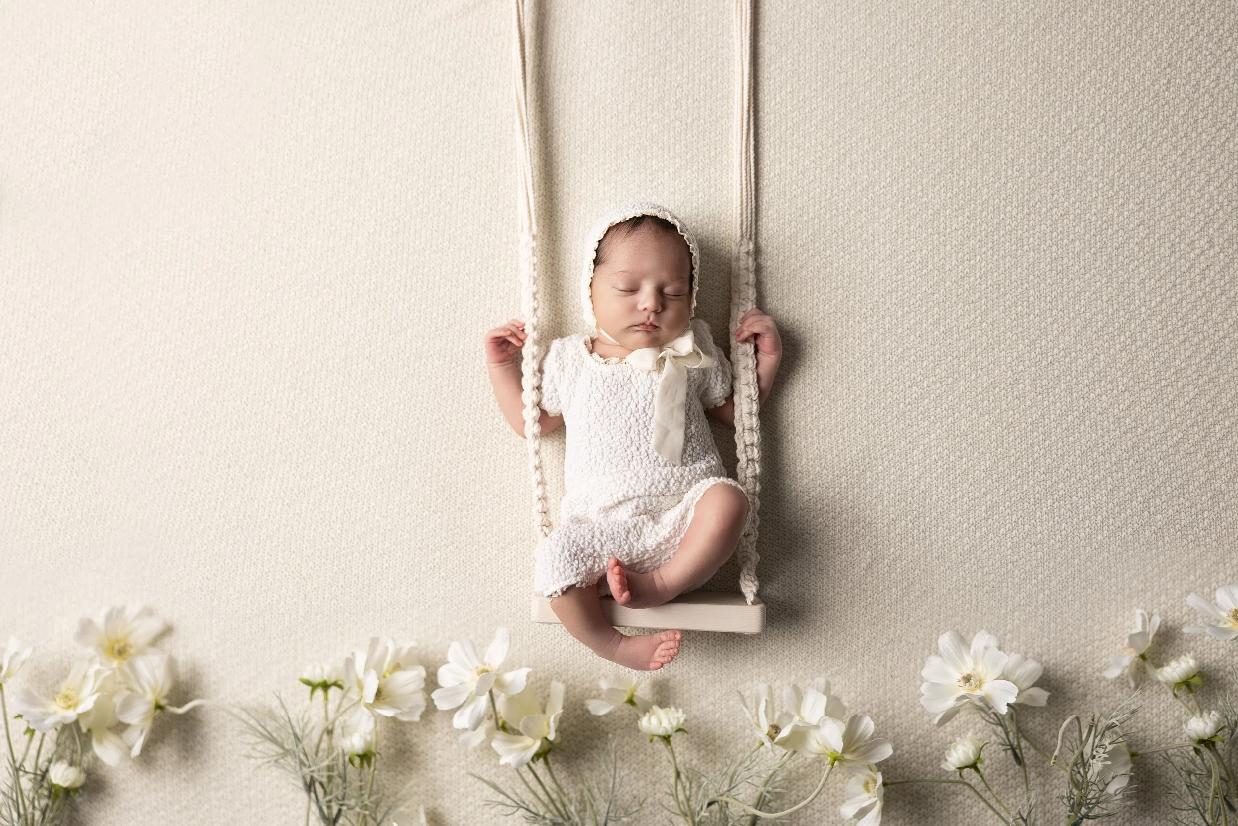 Newborn girl on swing with white floral accents