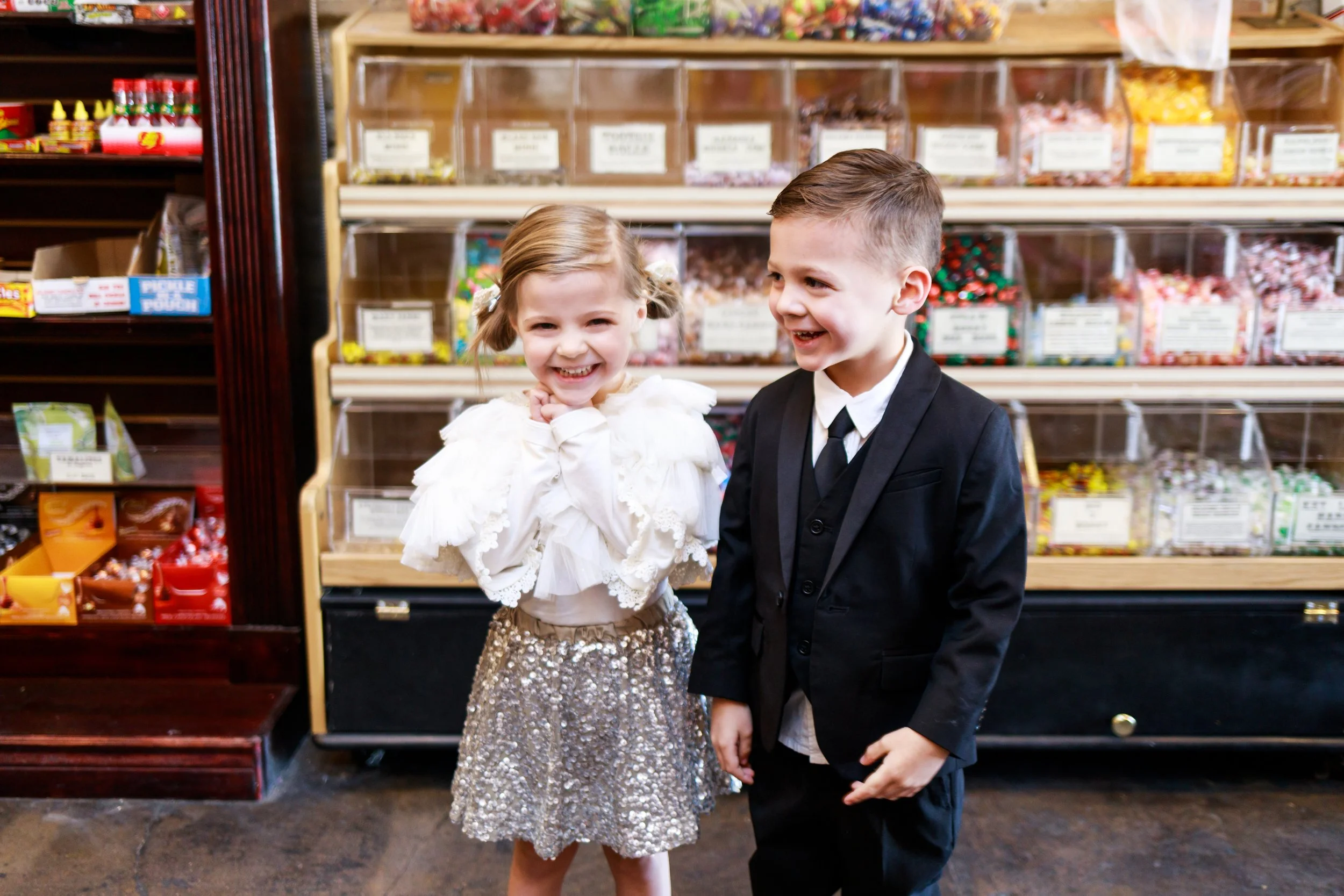 Smiling twins posing in front of candy wall