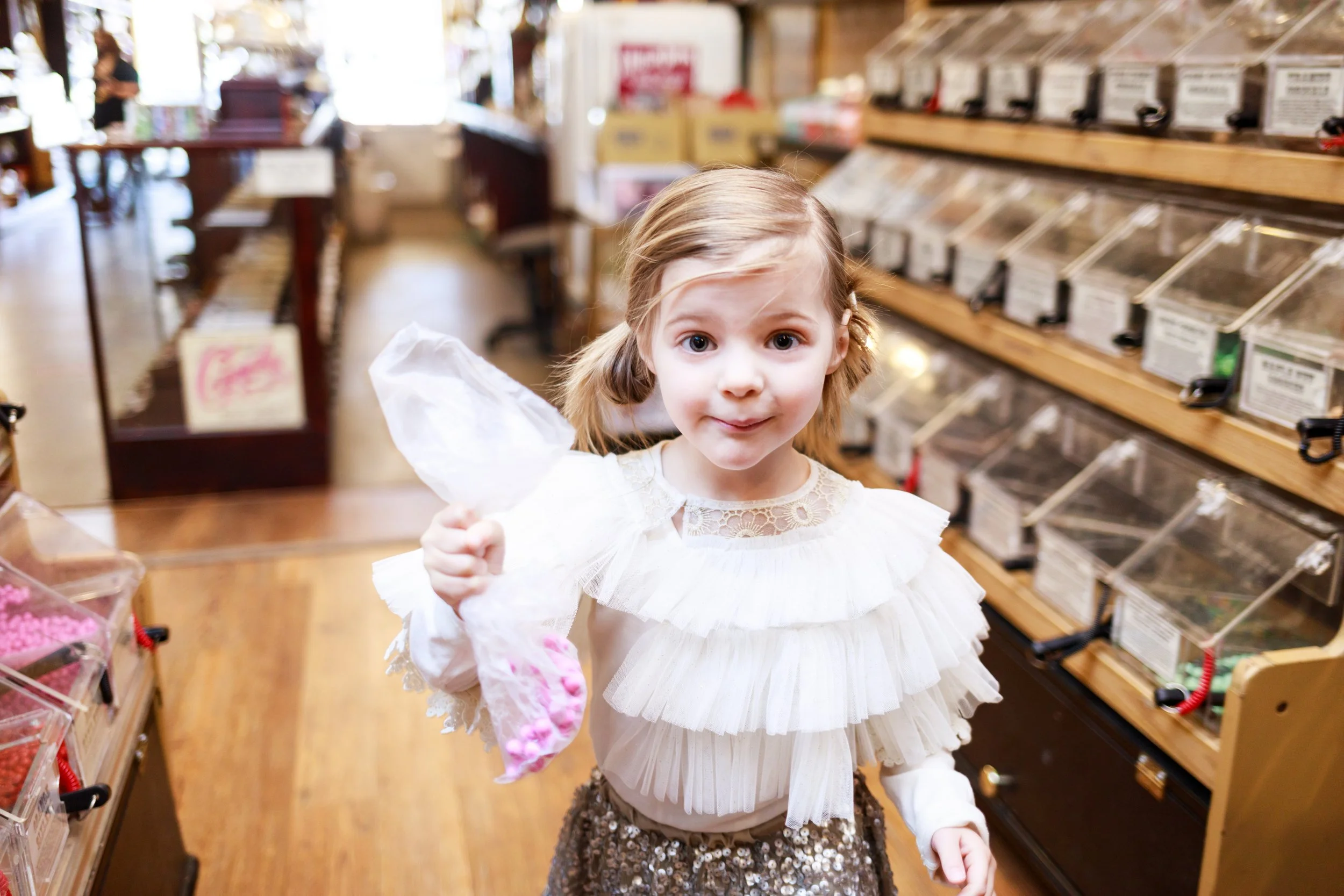 Little girl holding candy bag in store aisle