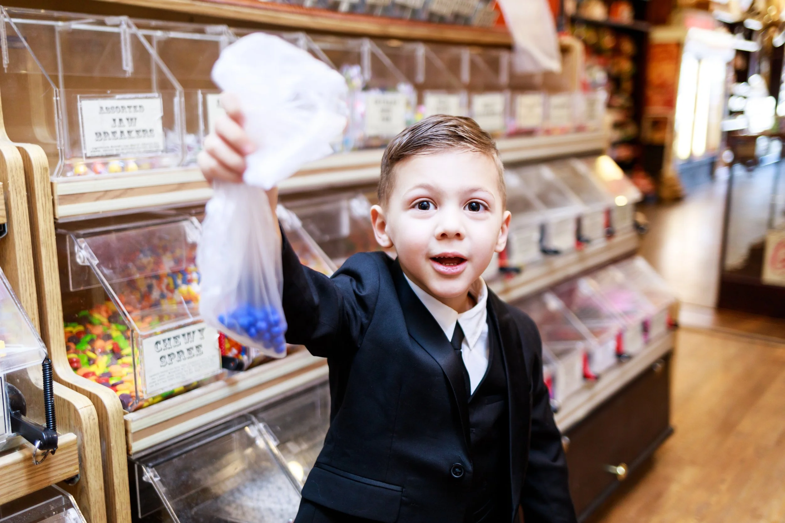 Little boy holding bag of candy in shop