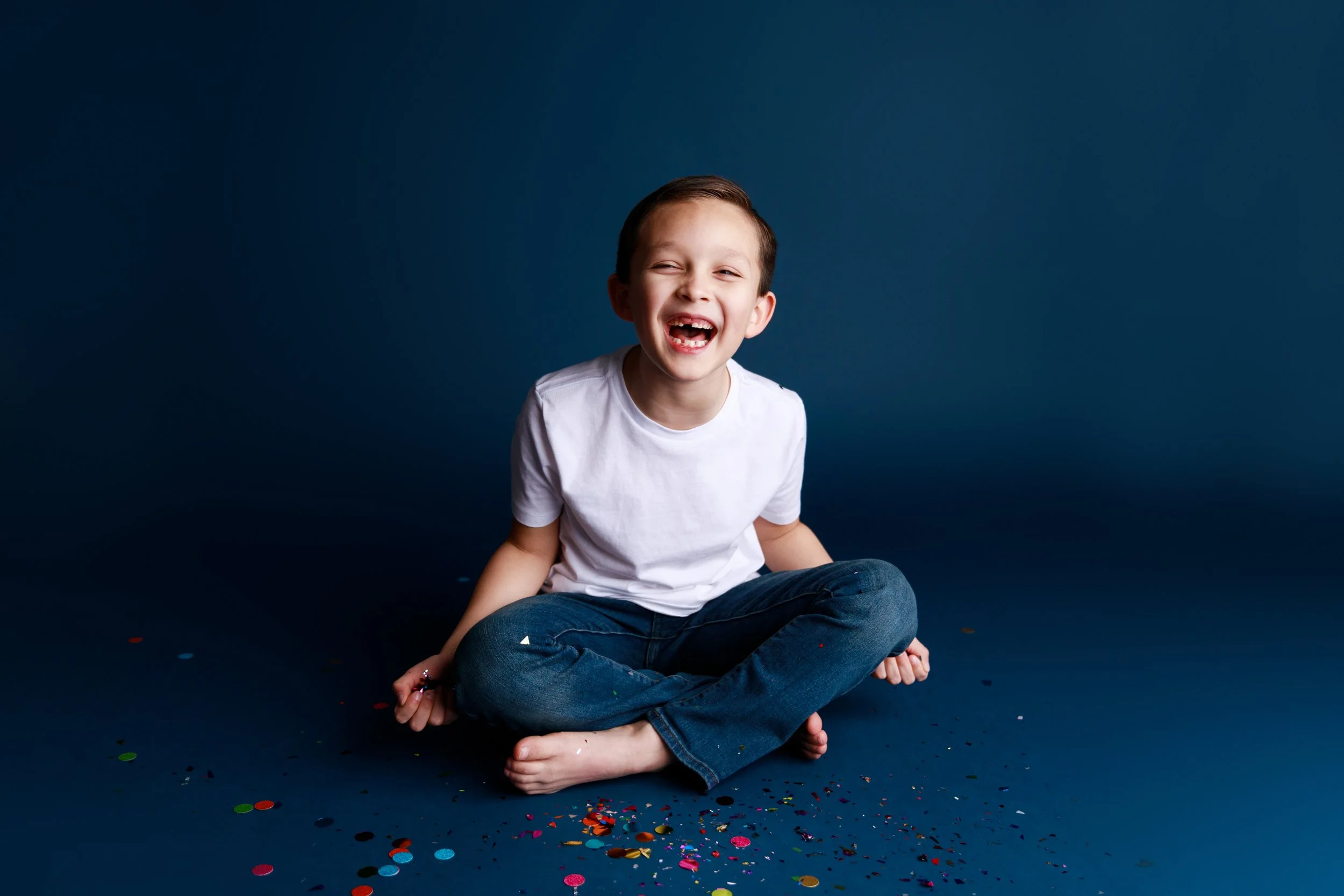 Laughing Boy Sitting in Confetti During Birthday Session