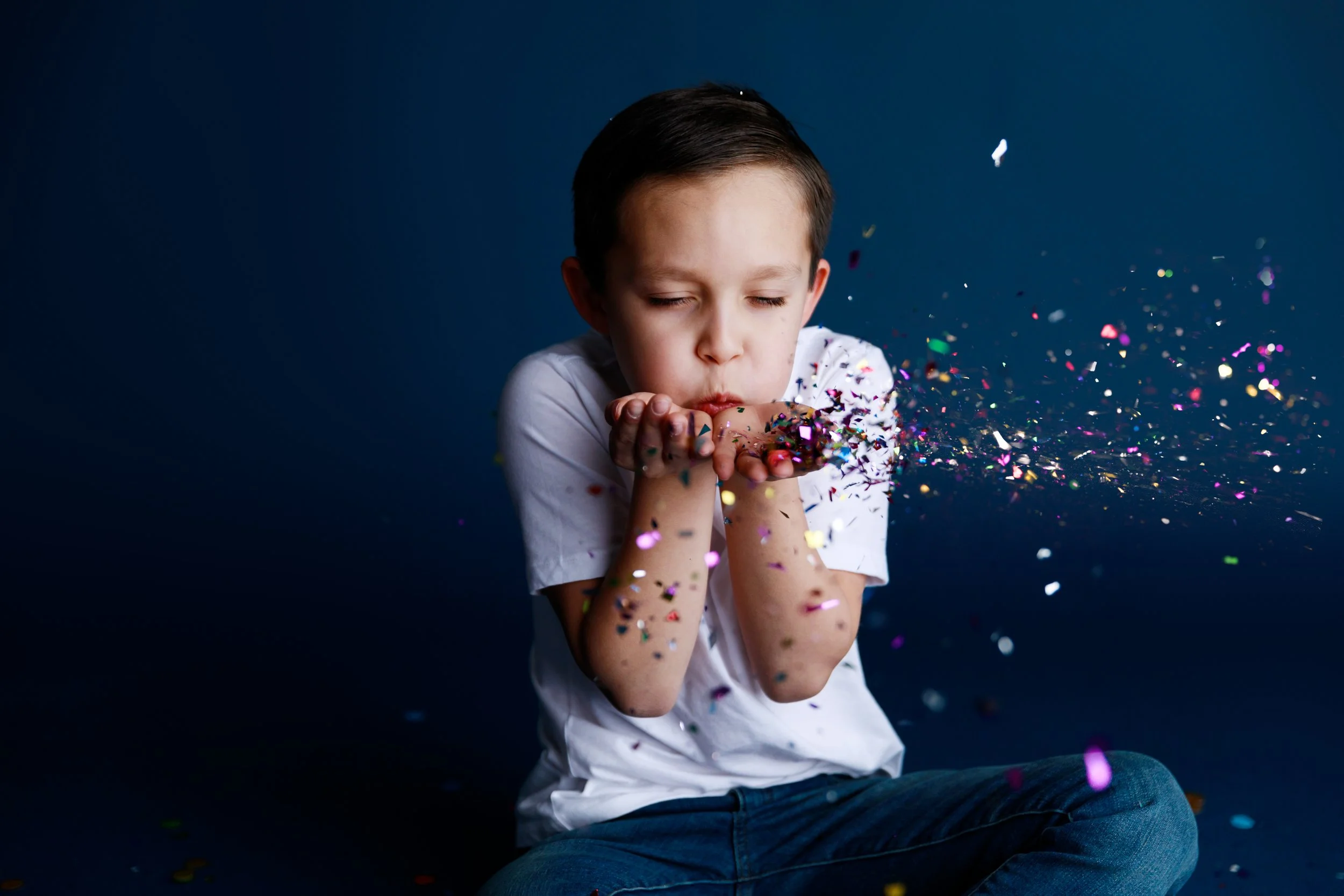 Boy Blowing Glitter Toward Camera in Studio Portrait