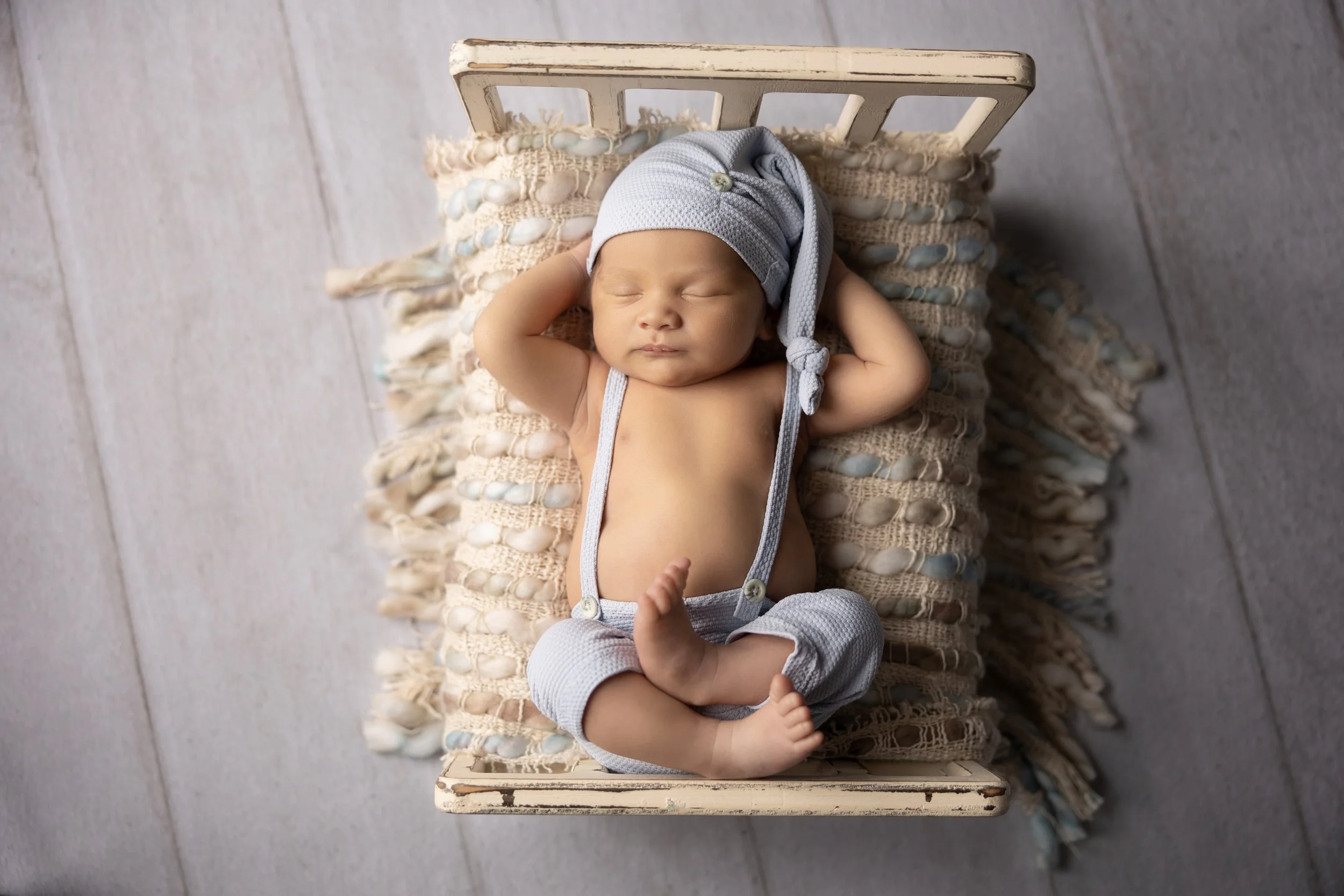 Relaxed Newborn Bed Pose with Hands Behind Head