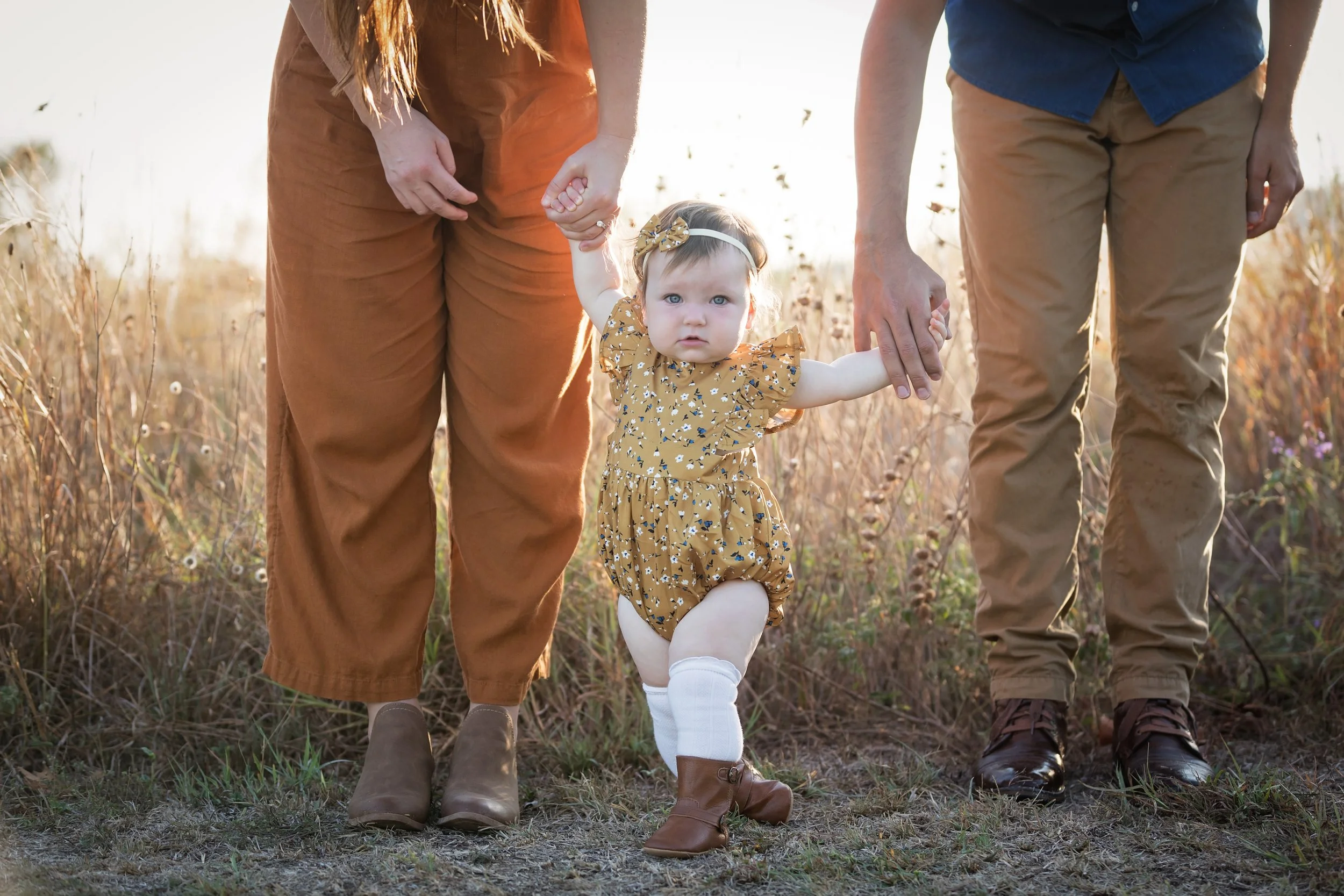 baby-walking-between-parents-outdoor-family-photos-austin.jpg