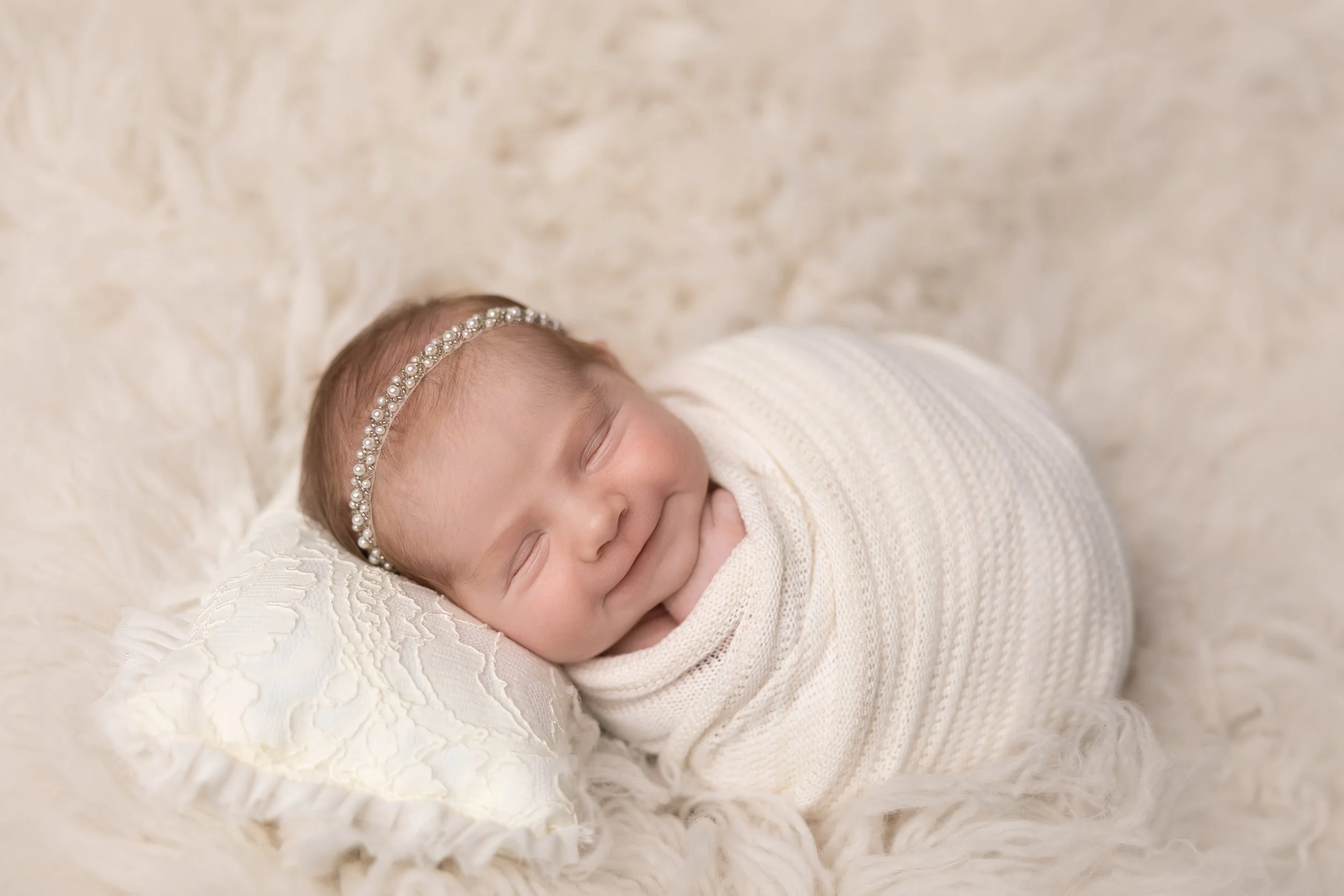 newborn baby girl in white monochromatic setup with matching tones